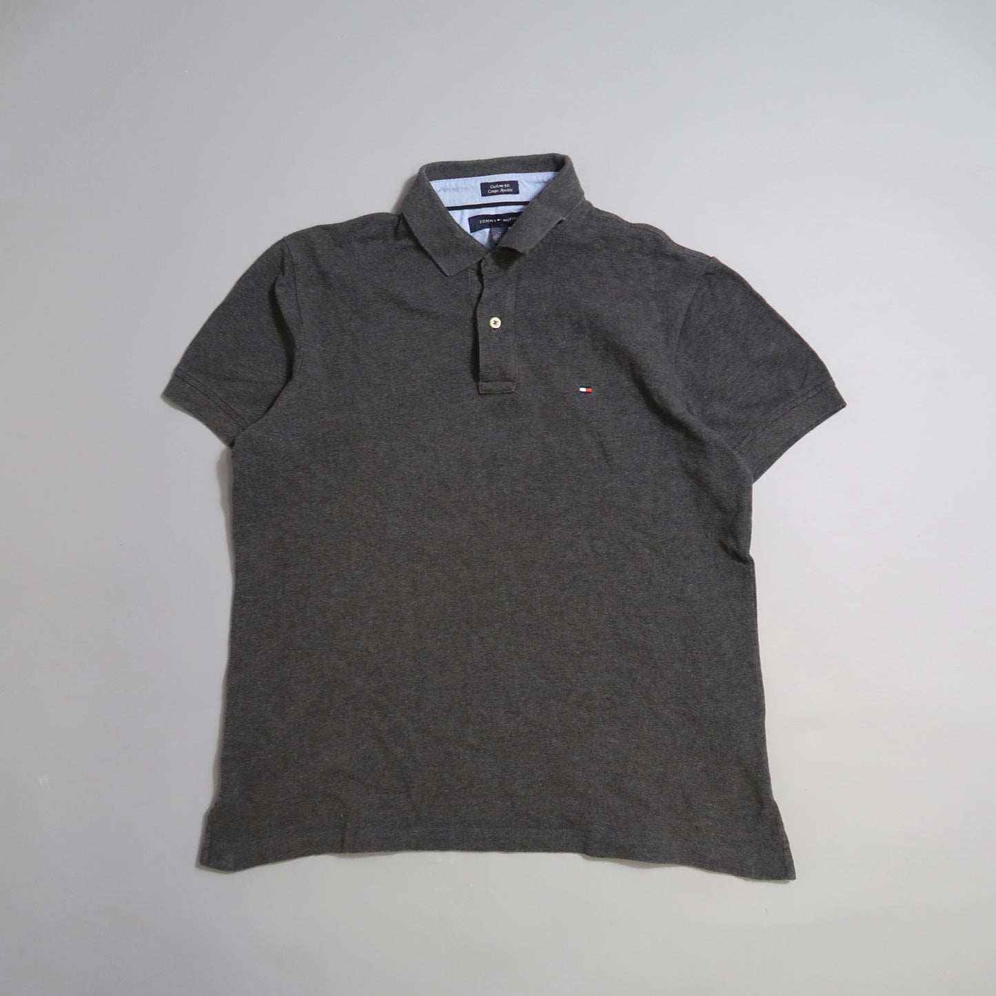 Dark gray polo shirt with a small logo on a plain background.