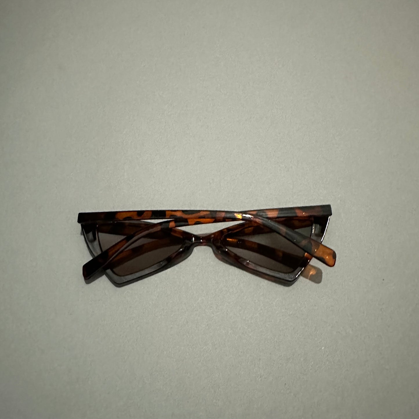 Tortoiseshell-patterned sunglasses on a plain background.