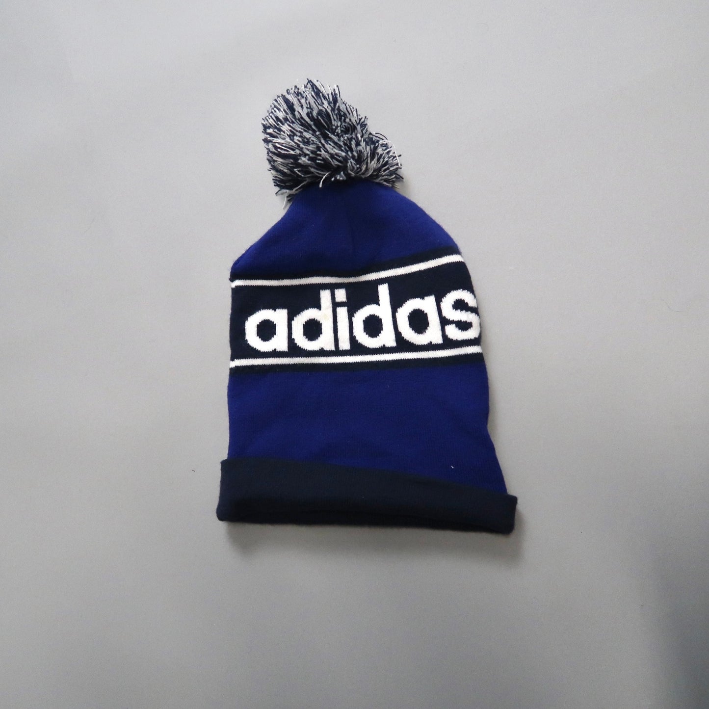 Blue Adidas beanie with pom-pom and logo on front.