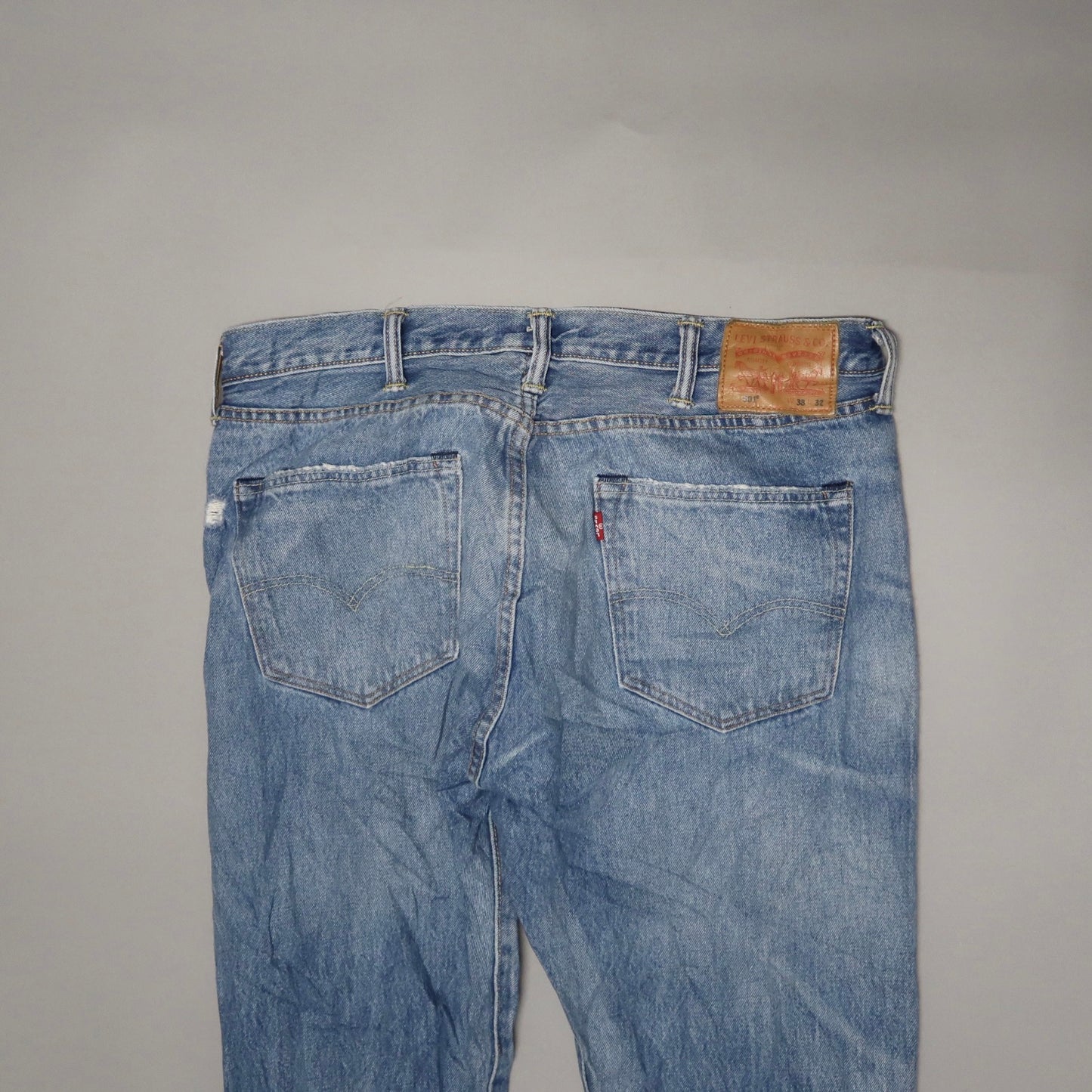 Back view of light blue jeans with pockets and a leather patch.