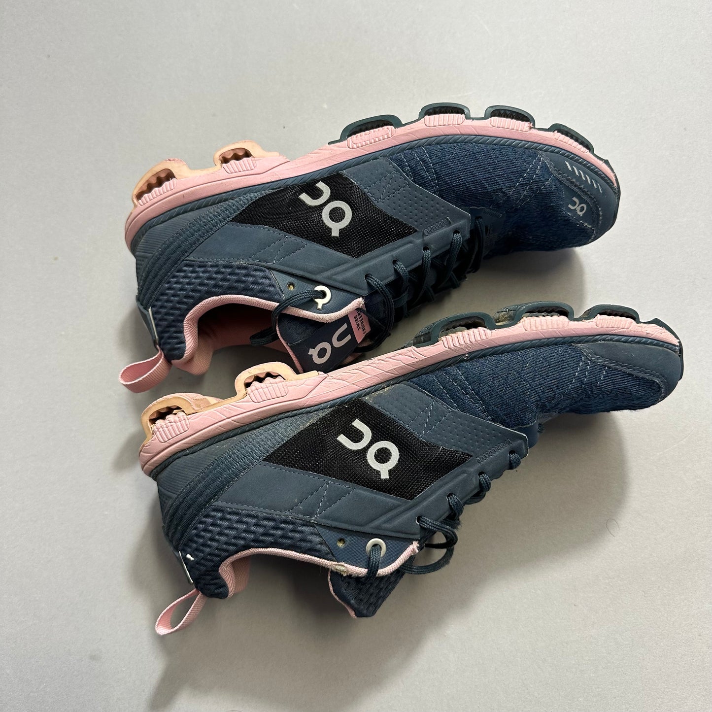 Blue and pink sneakers with distinctive sole design on a gray surface.