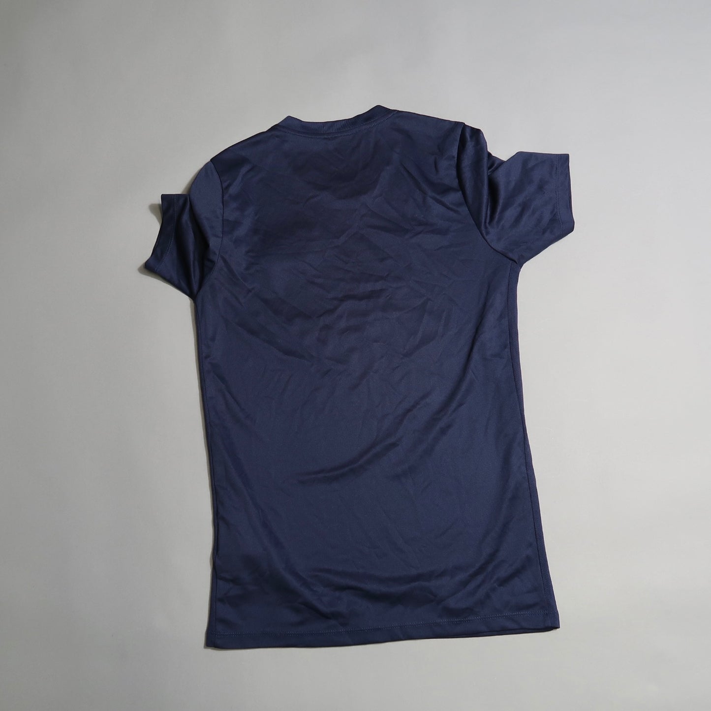 Back view of a plain navy blue t-shirt on a gray background.