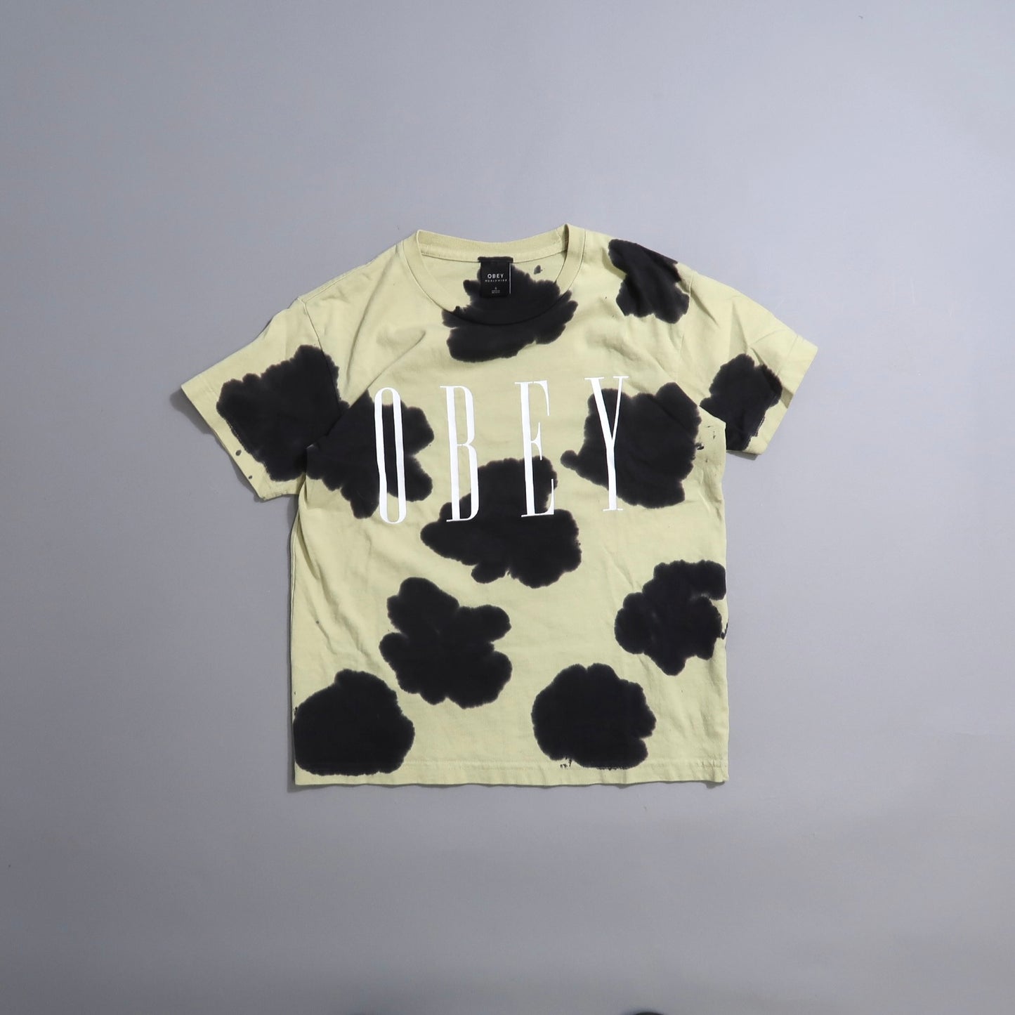Beige t-shirt with black splotches and nullOBEYnull text.