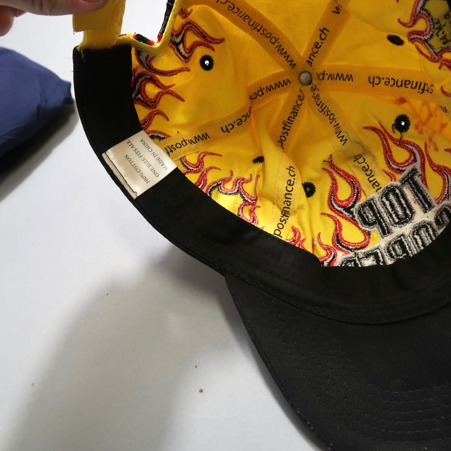 Inside of a black cap with yellow flame design and text.