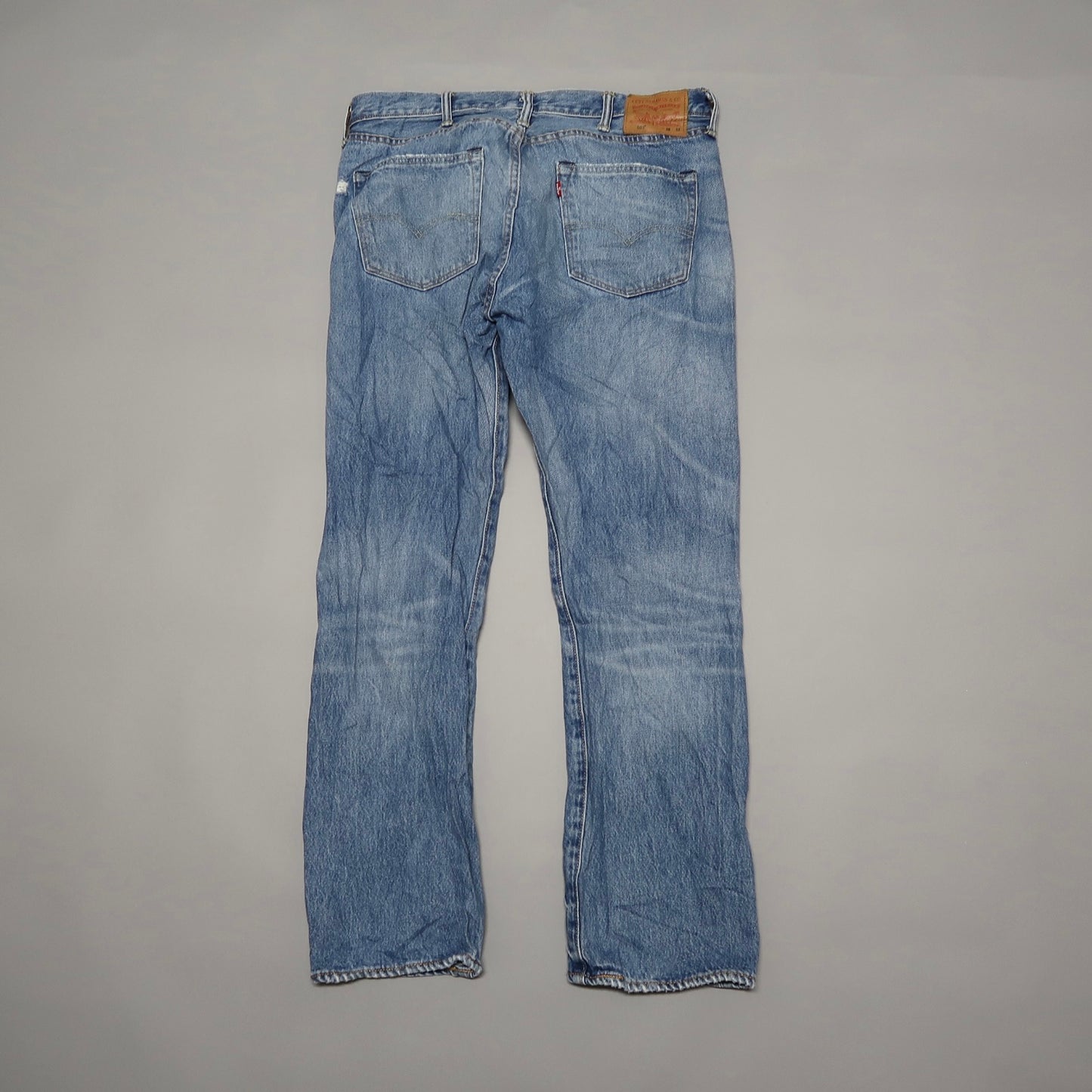 Back view of faded blue jeans on a flat surface.