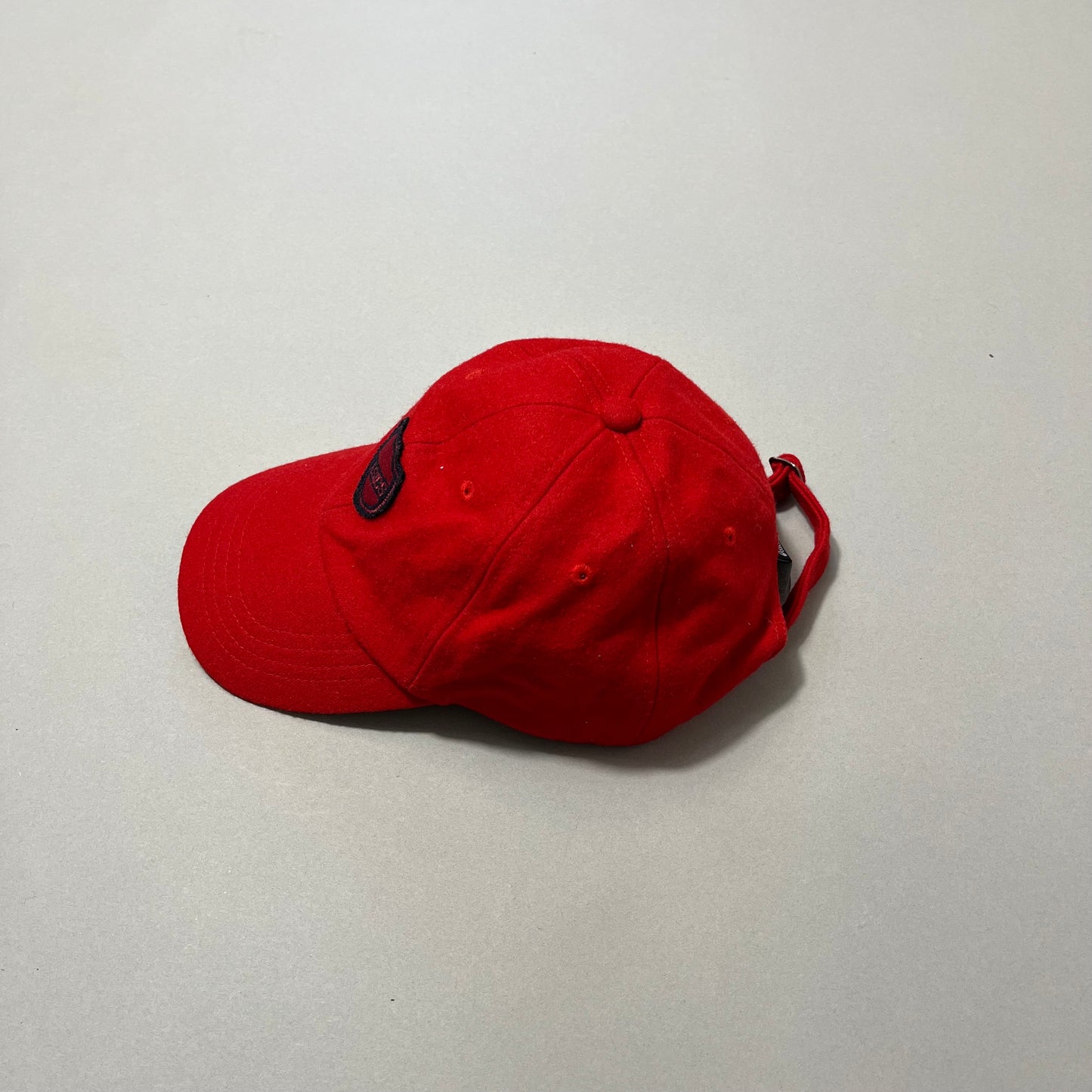 Red baseball cap with a patch on a neutral background.