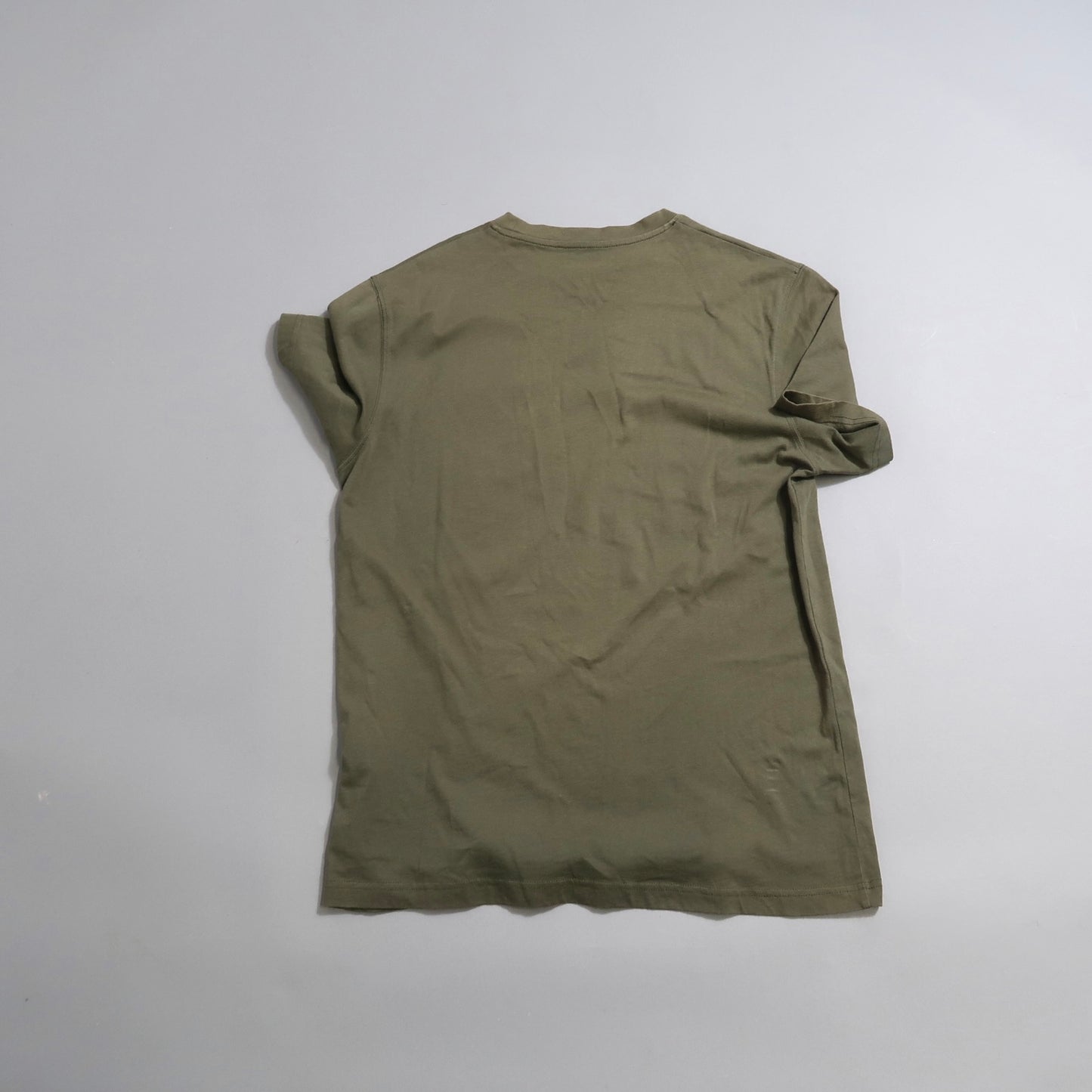 Back view of a plain olive green T-shirt on a gray surface.