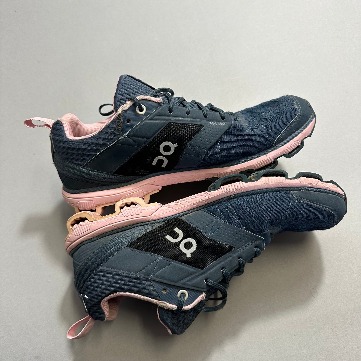 Blue and pink athletic shoes with unique sole design on grey surface.