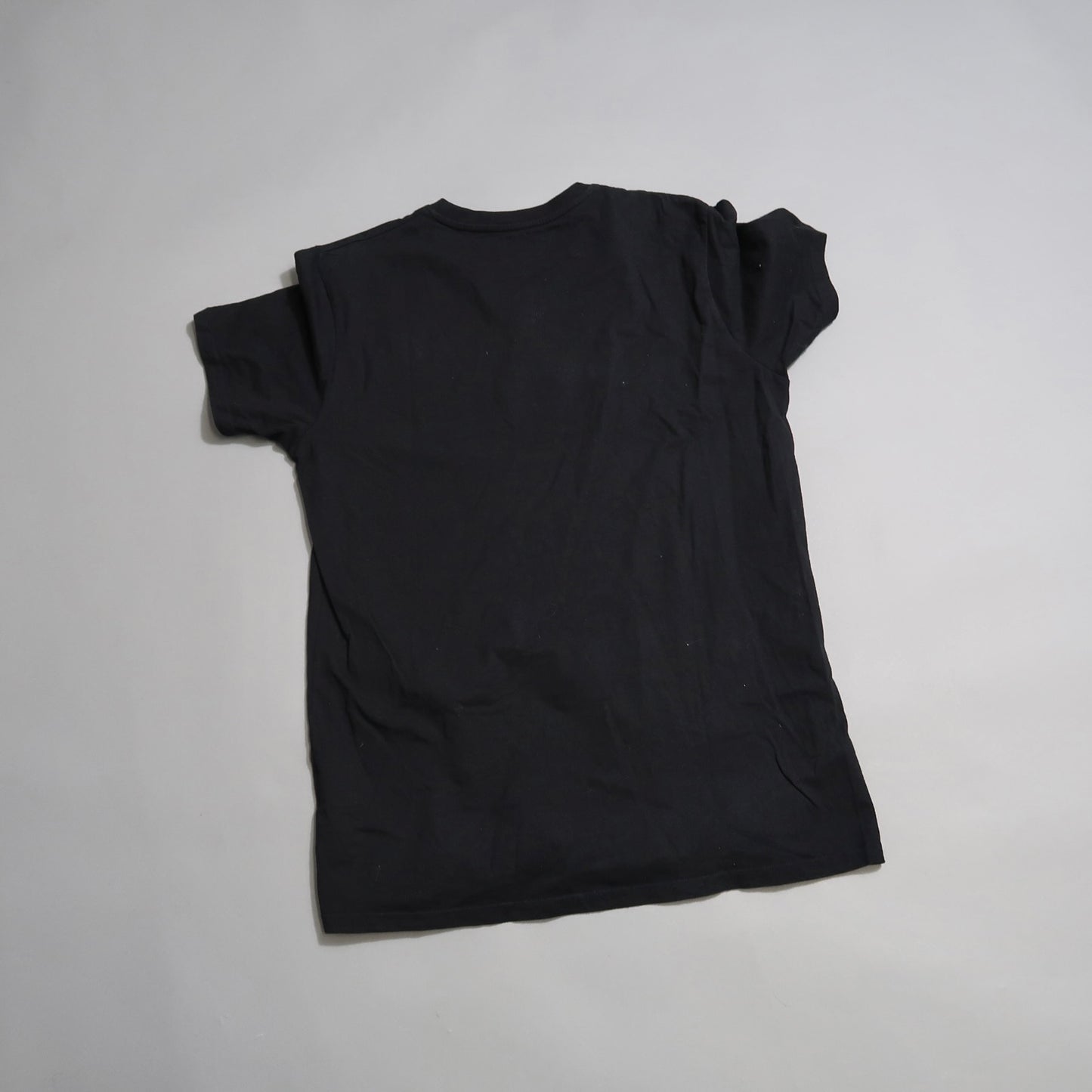 Black t-shirt laid flat on a light gray background.