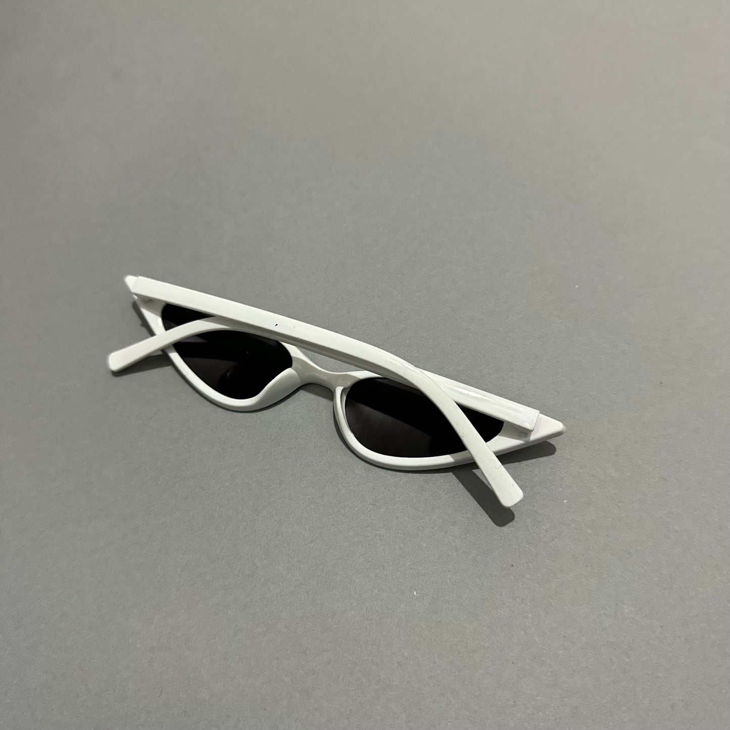 White cat-eye sunglasses on a gray surface.
