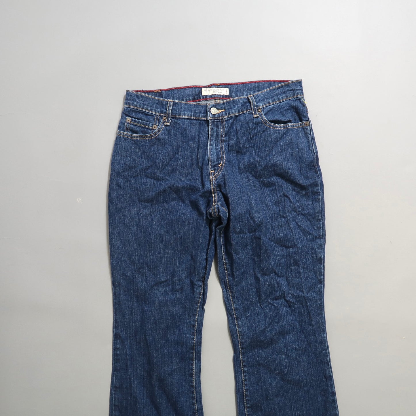 Blue denim jeans with a button and zip closure on a plain background.