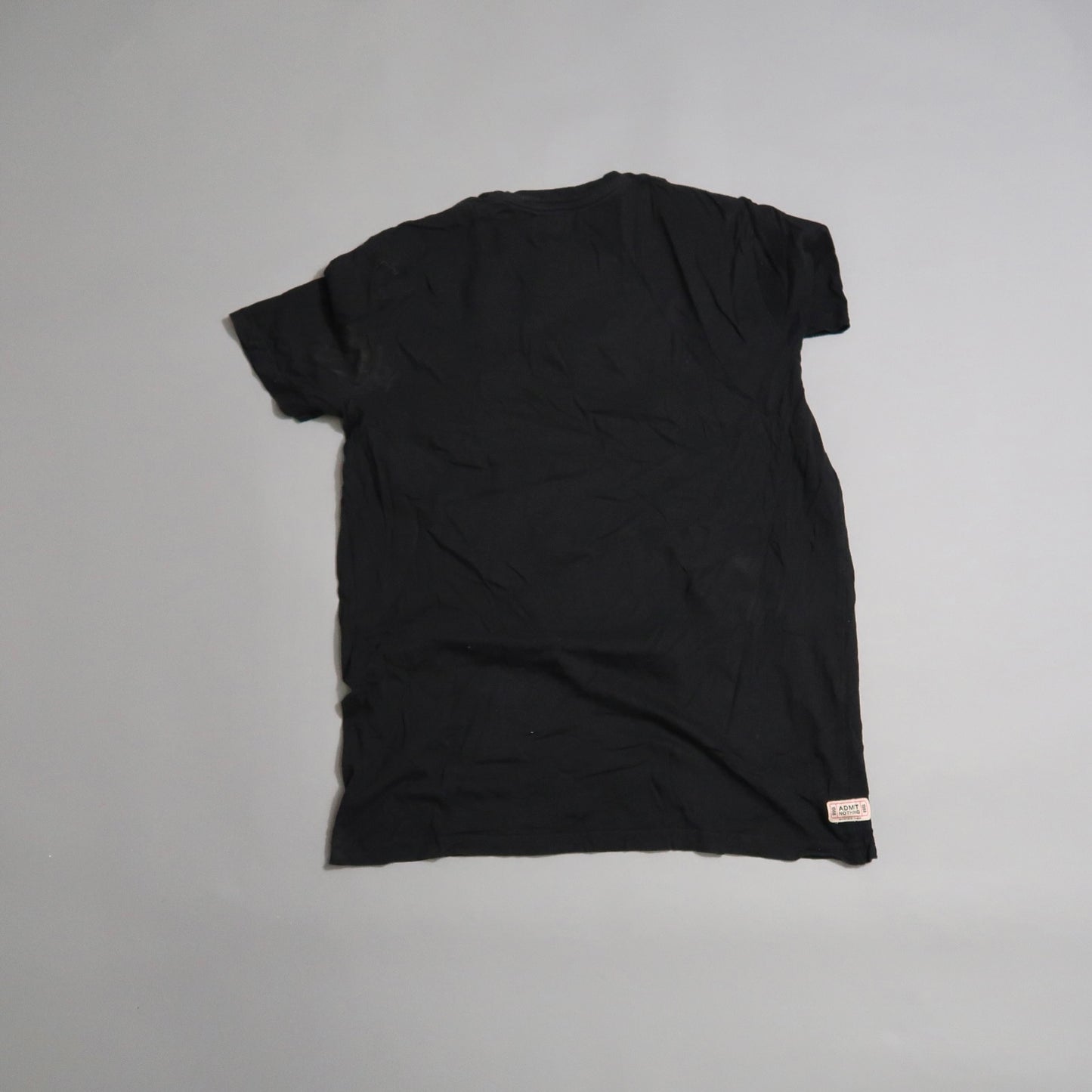 Wrinkled black T-shirt laid flat on a light surface.