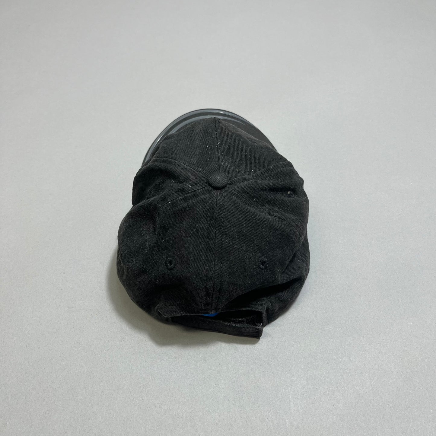 Black baseball cap lying on a gray surface, front view.