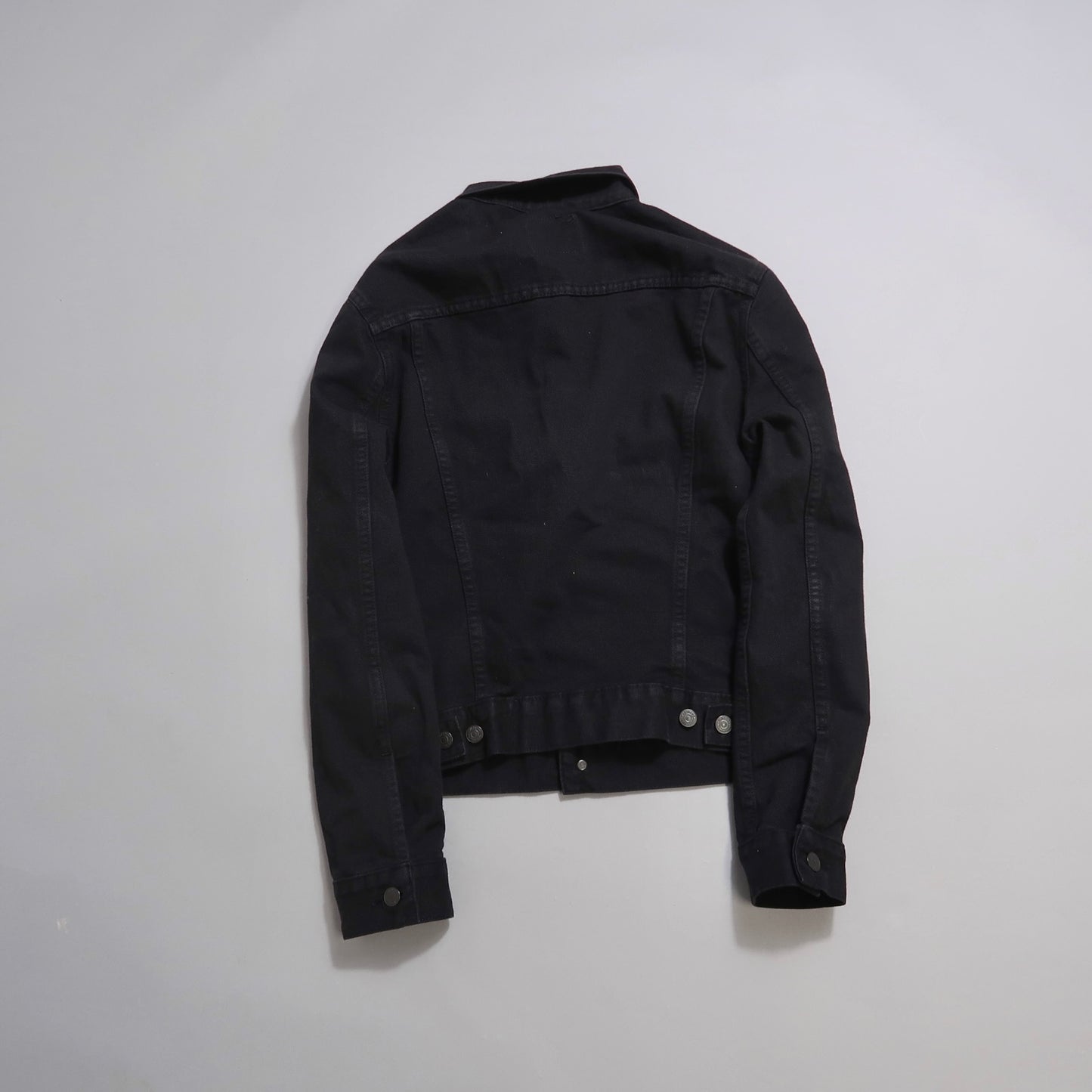 Black denim jacket displayed on a gray background.