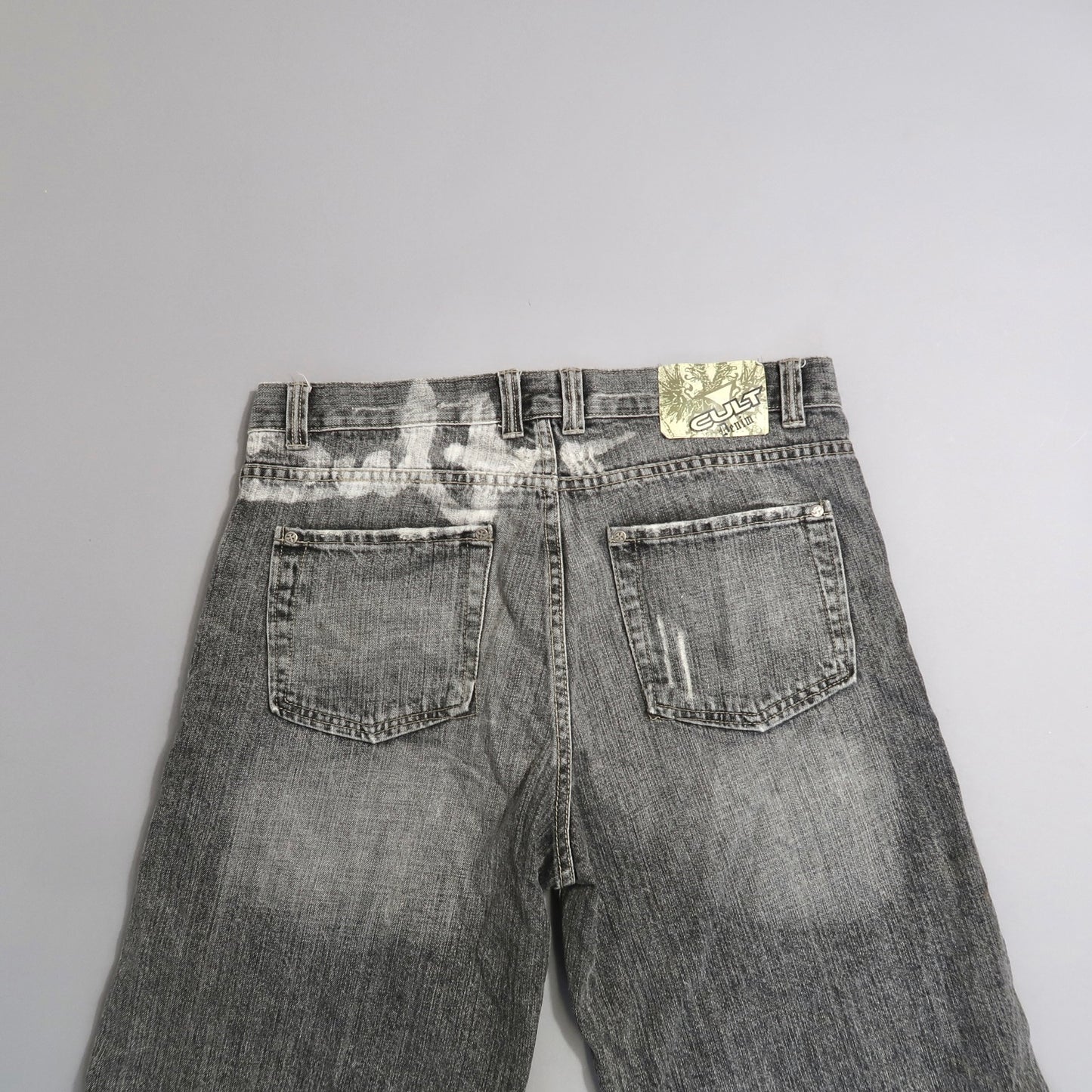 Back view of faded gray jeans with a nullCultnull label on the waistband.