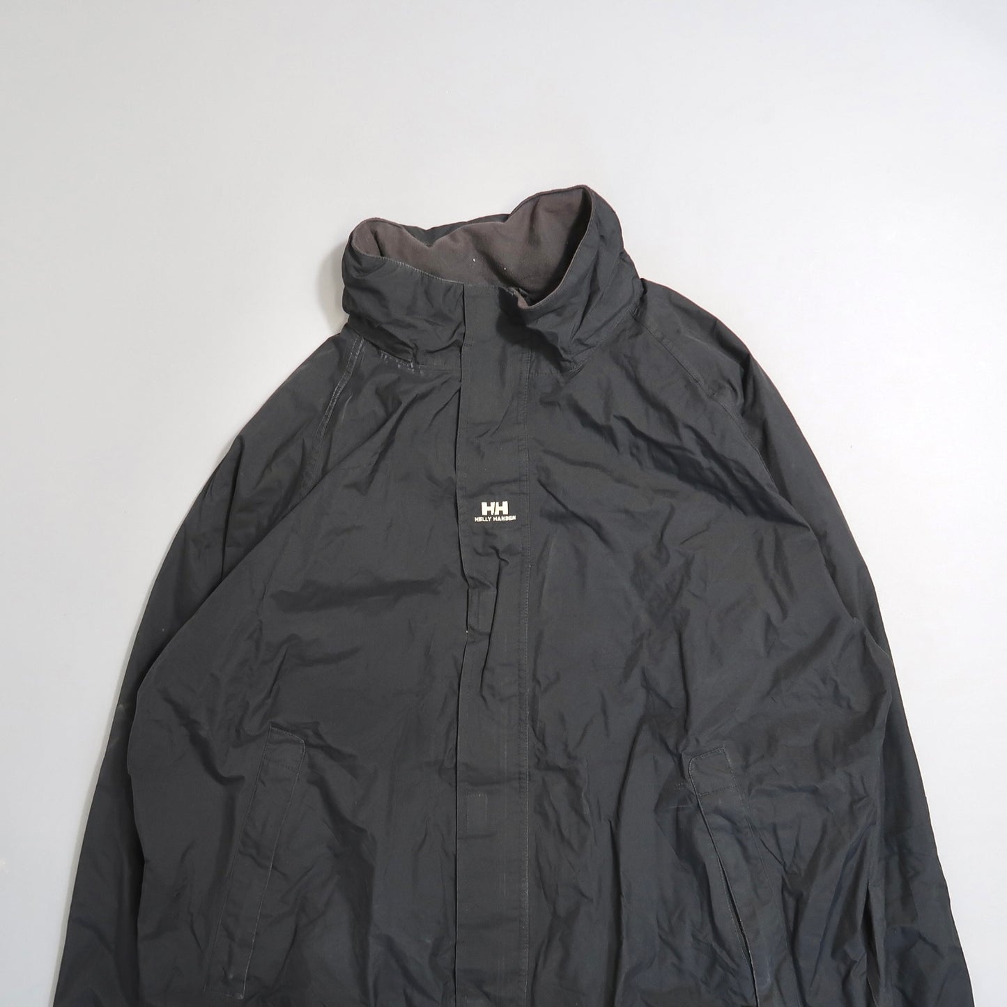 Black Helly Hansen jacket on a plain background.