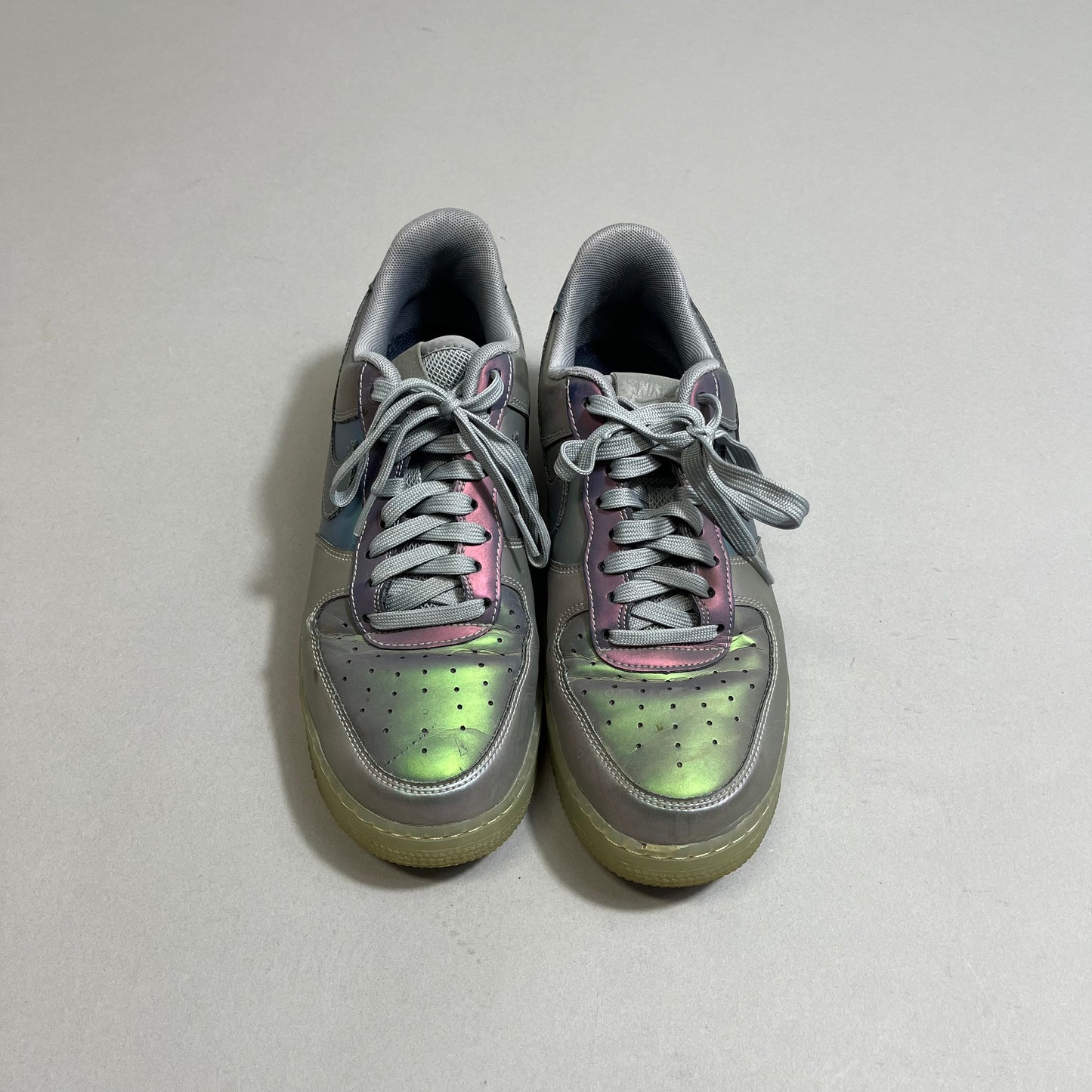 Gray sneakers with iridescent green and pink accents on a neutral background.