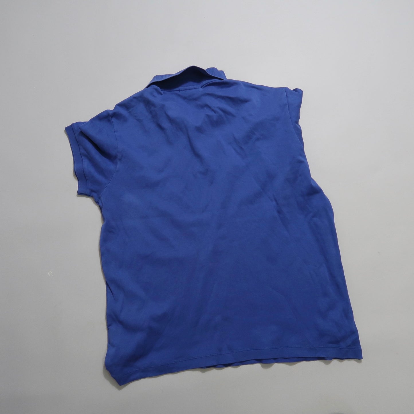 Blue collared shirt laid flat on a gray surface.