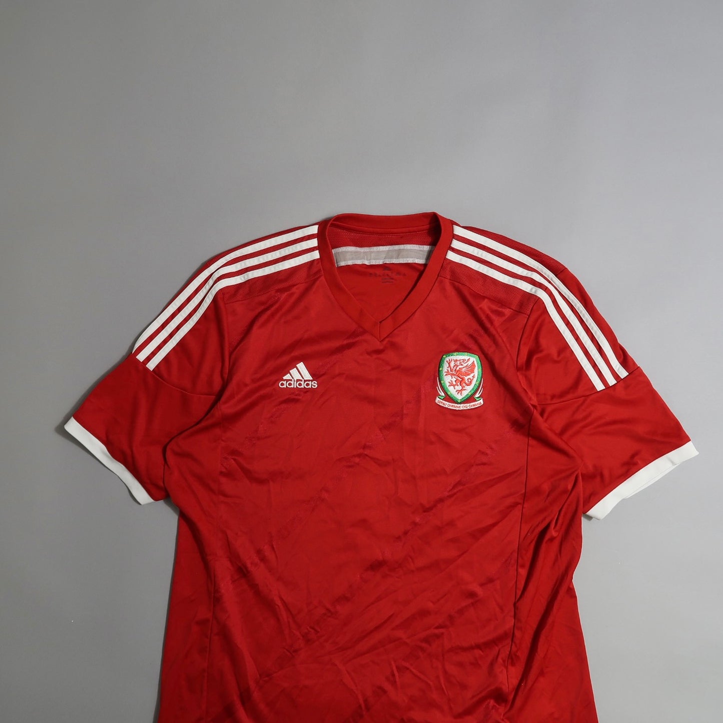 Red Adidas jersey with white stripes and Welsh crest.