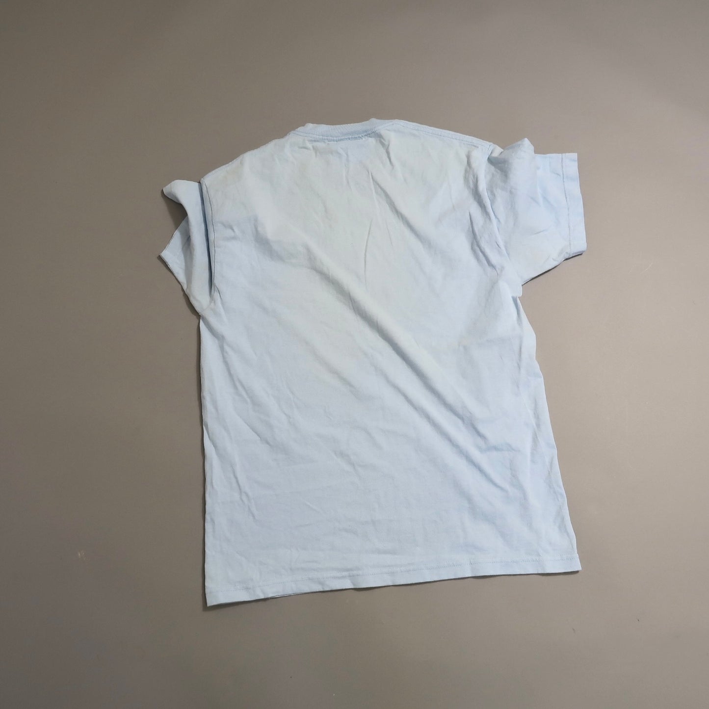 Light blue T-shirt laying flat on a neutral background.