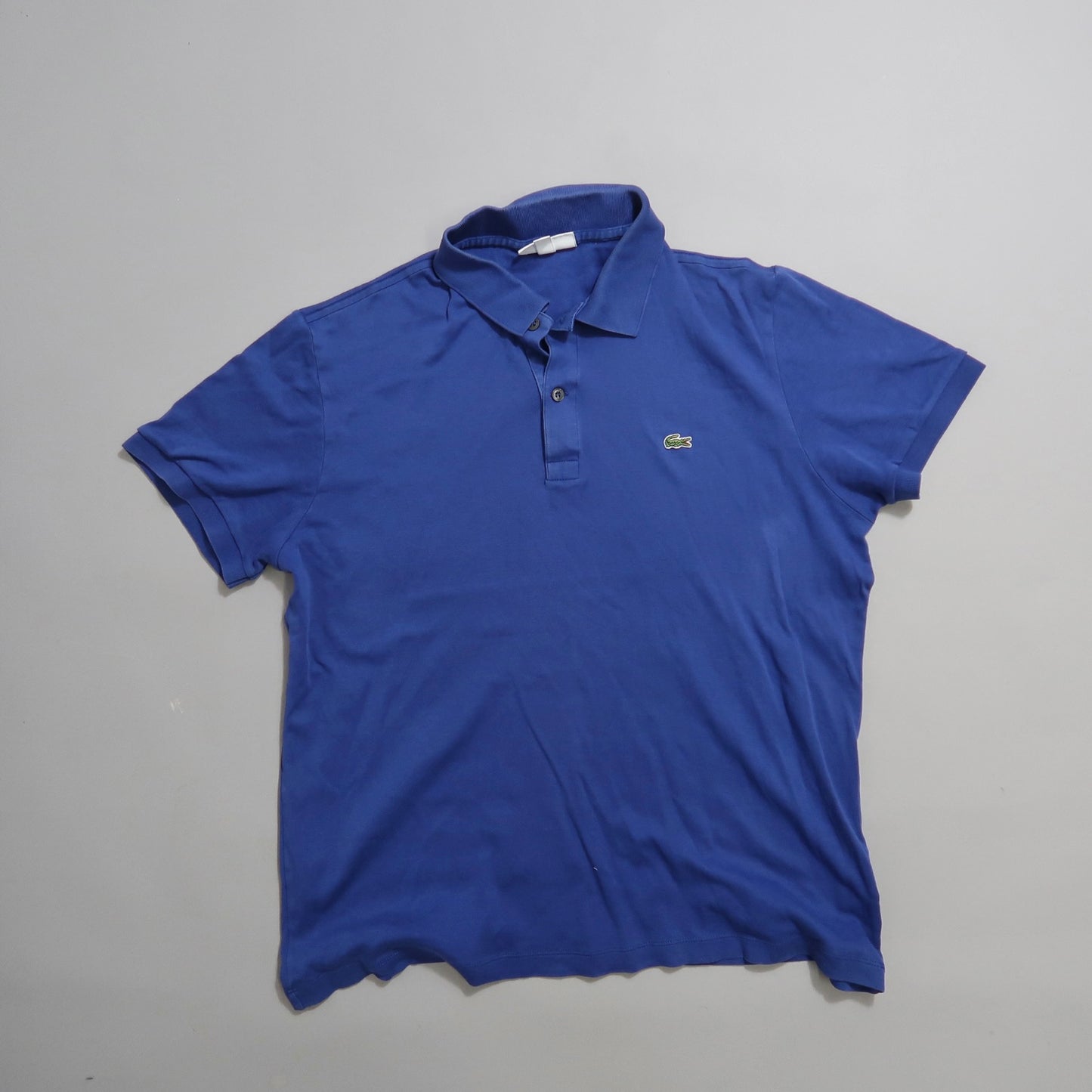 Blue polo shirt with a logo on the chest, laid flat.