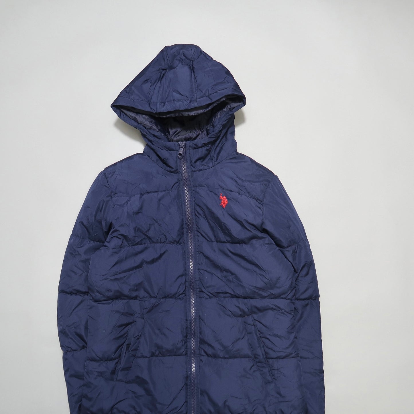 Dark blue puffer jacket with a hood and a red logo on the chest.