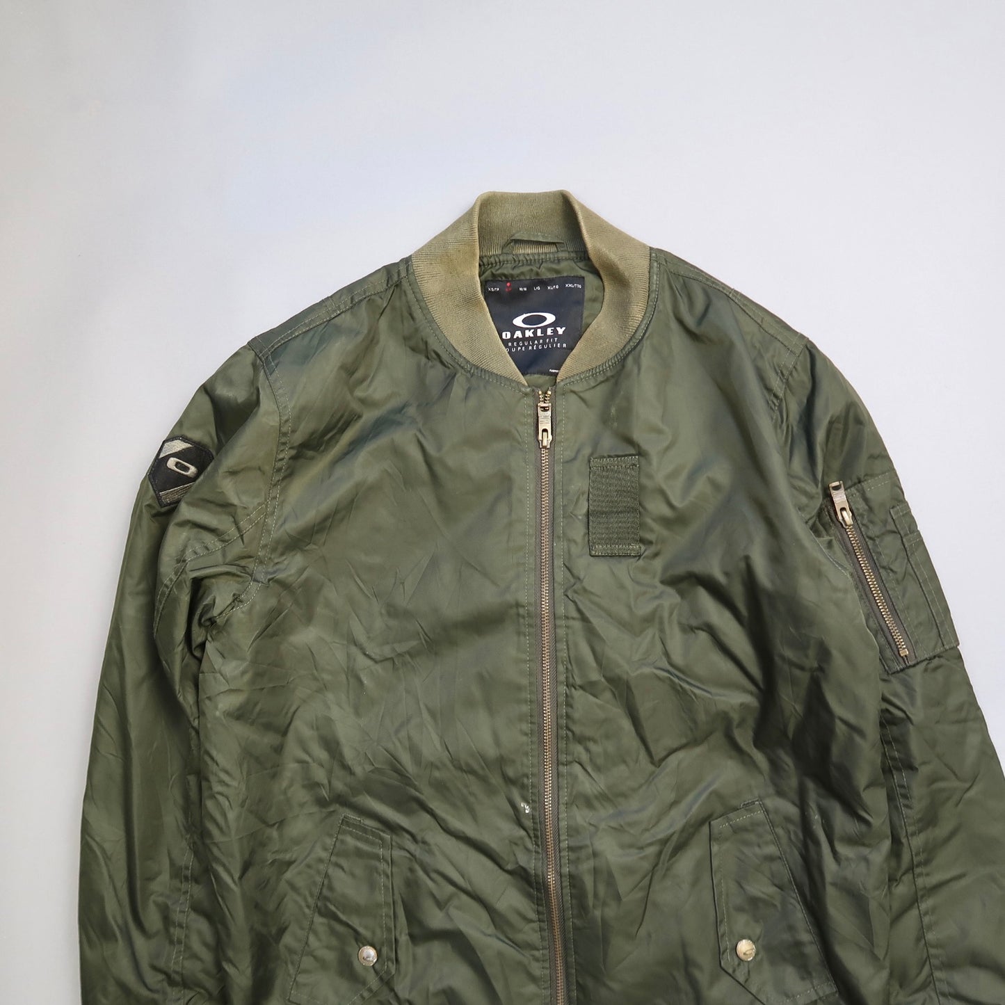 Green bomber jacket with zipper details and patches.