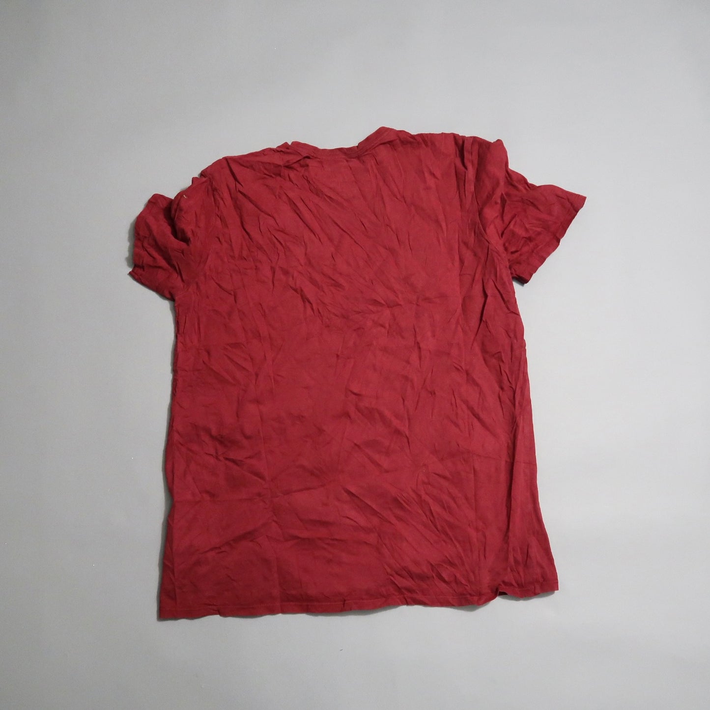 Wrinkled red T-shirt lying on a flat surface.