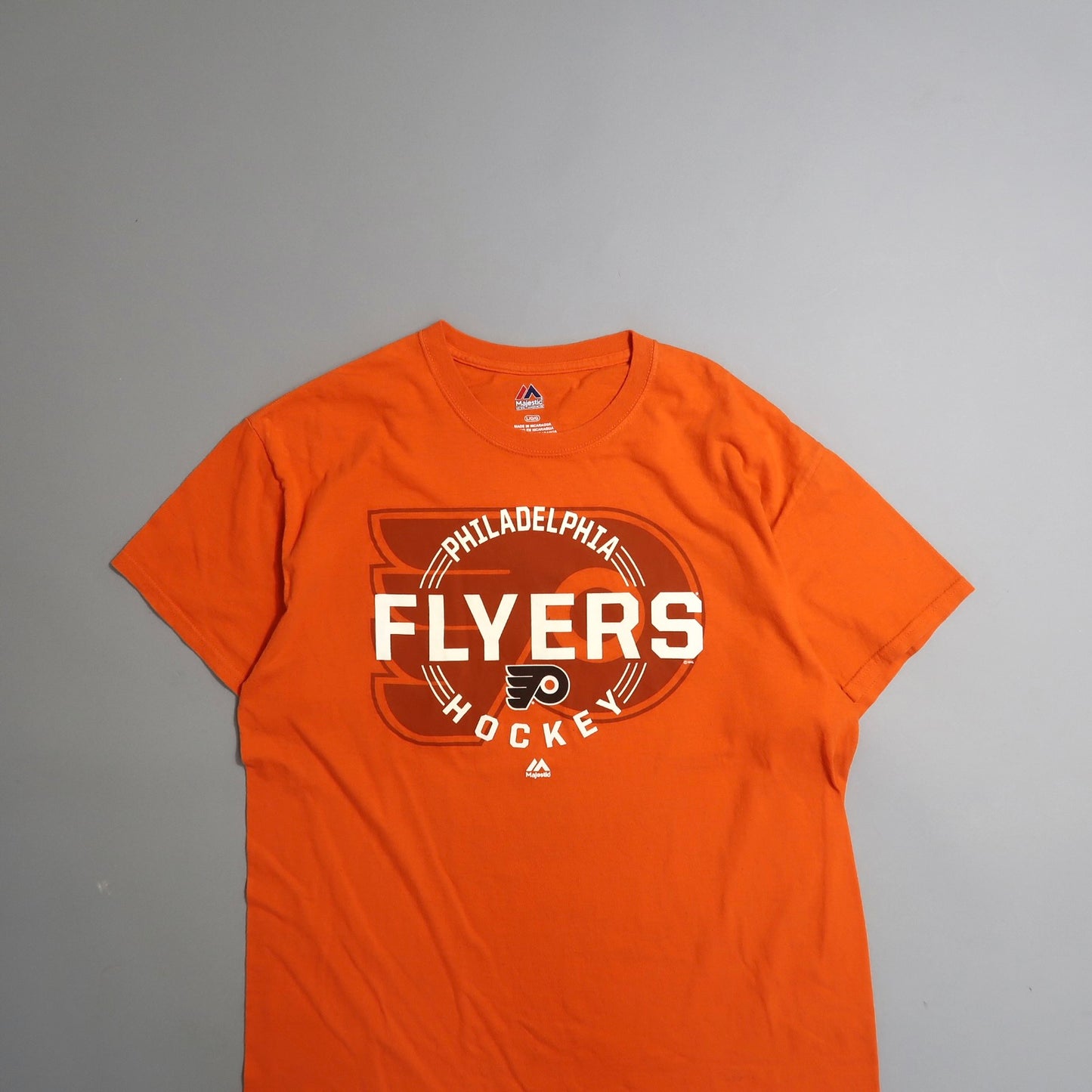 Orange Philadelphia Flyers hockey T-shirt on a gray background.