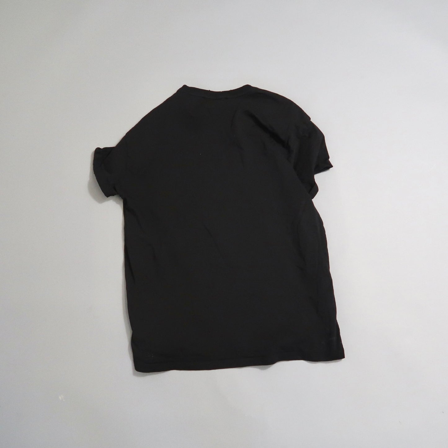 Black t-shirt laid flat on a plain white surface.