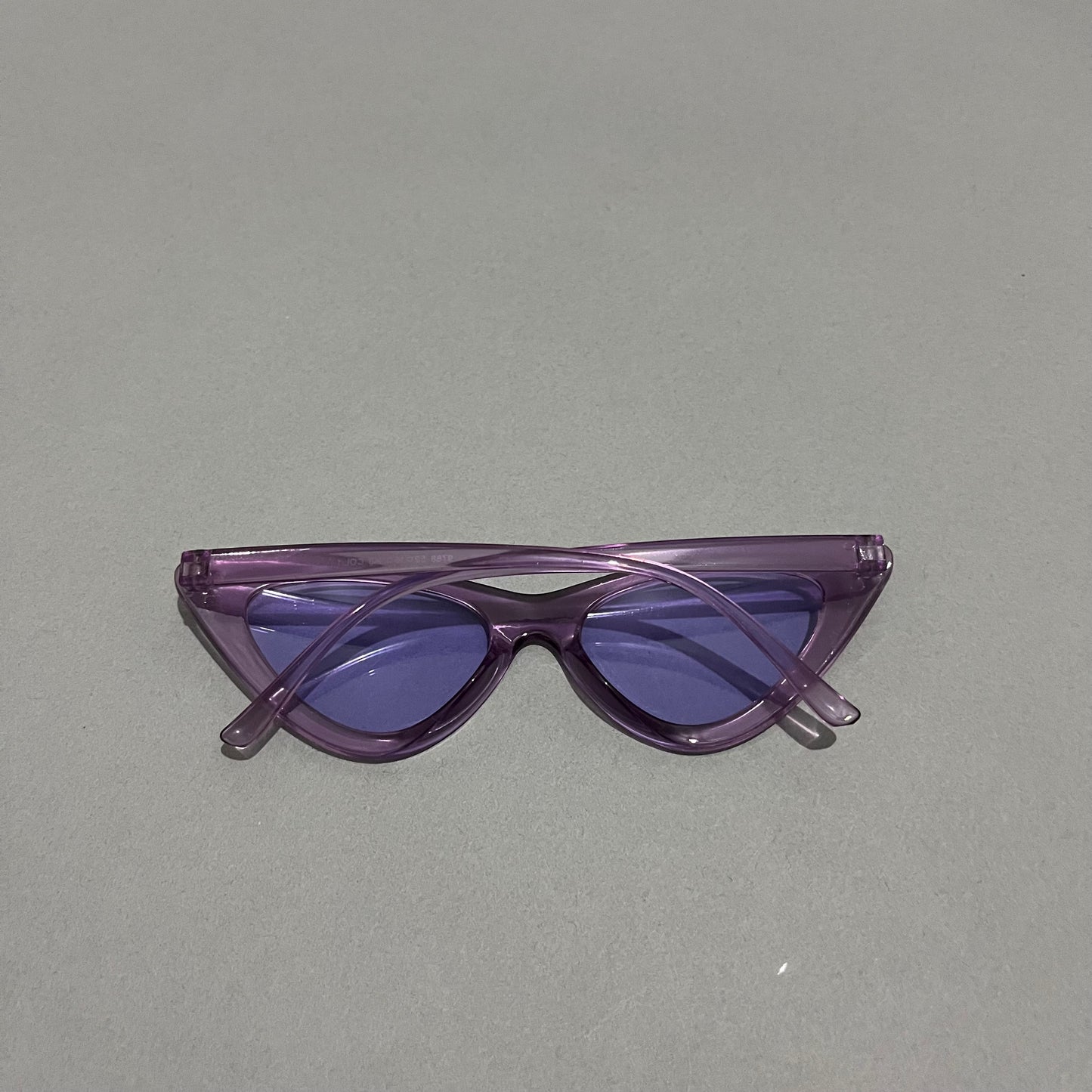 Purple cat-eye sunglasses on a gray background.