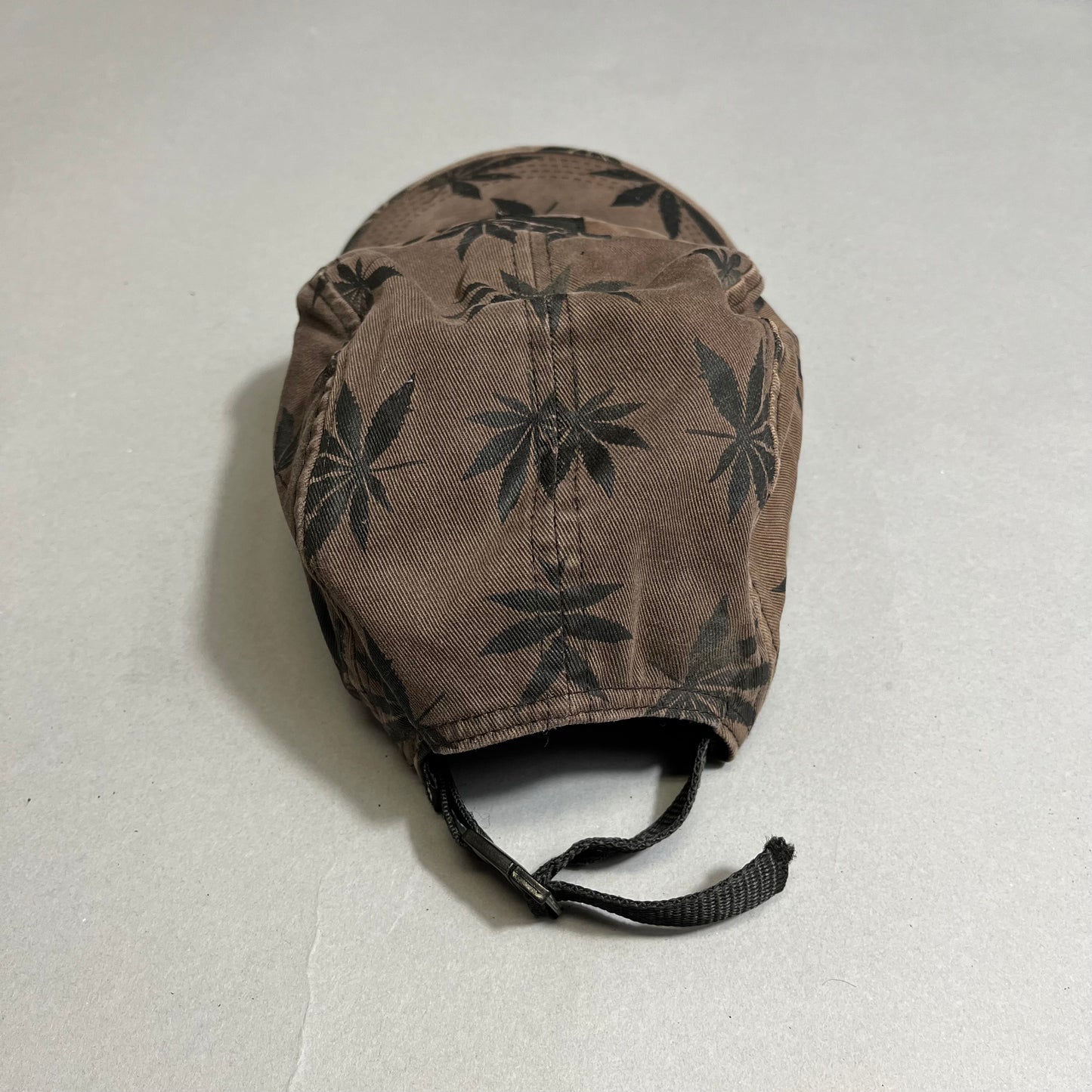 Brown cap with black leaf pattern on a gray background.