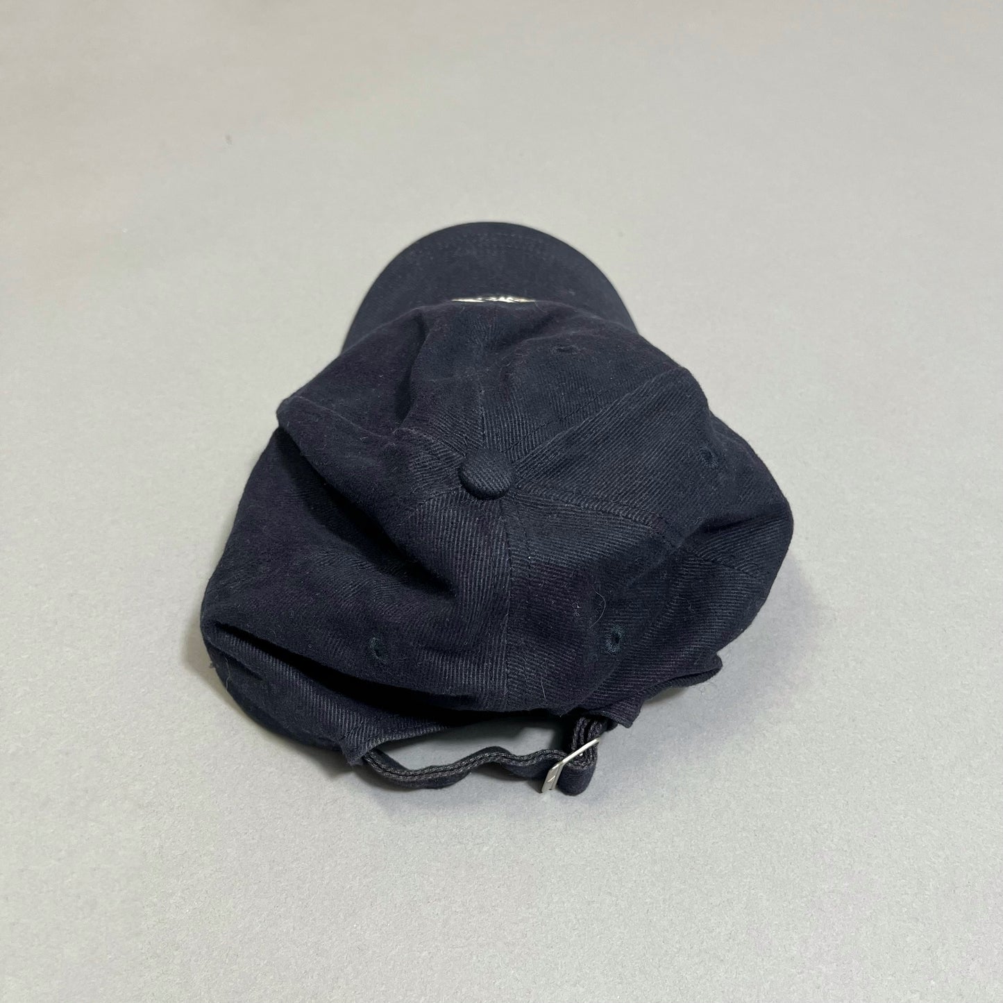 Black baseball cap on a gray background, seen from the top.