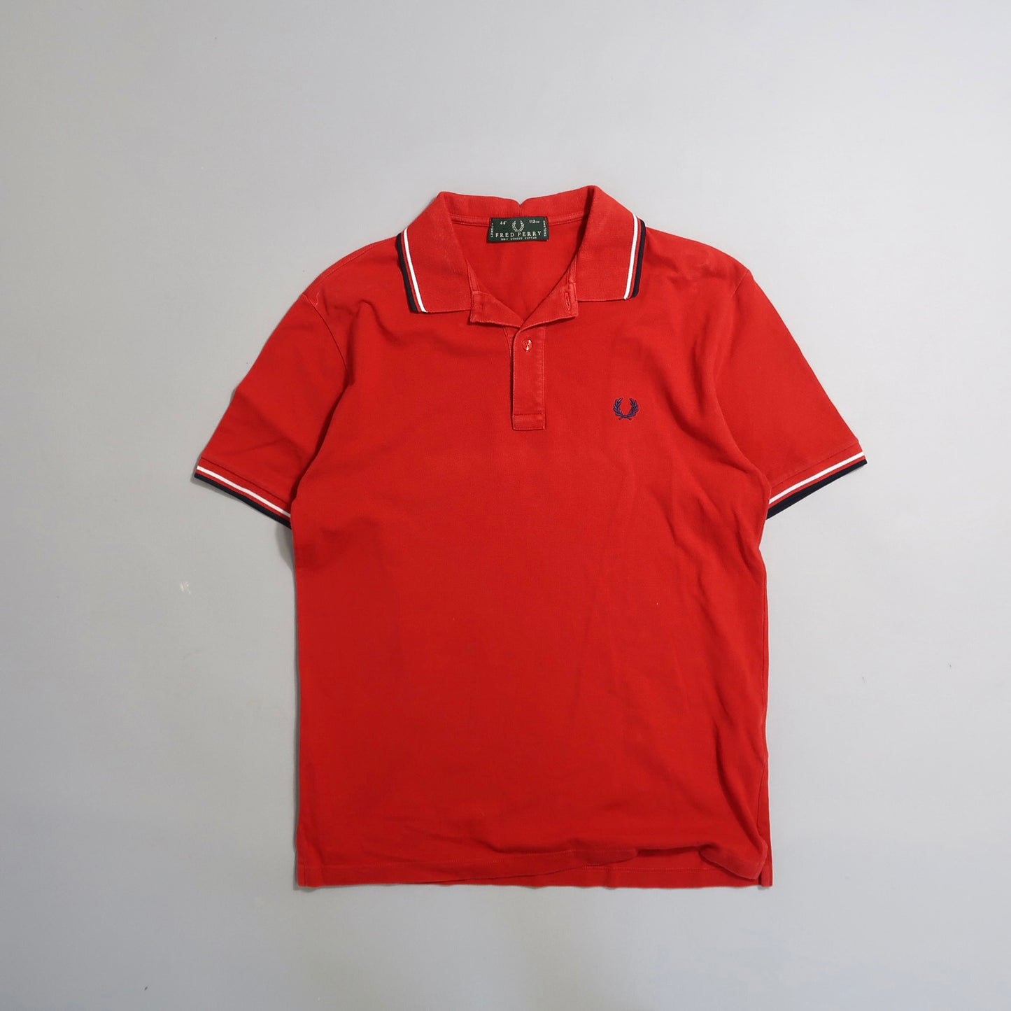 Red polo shirt with white and navy trim on collar and sleeves.