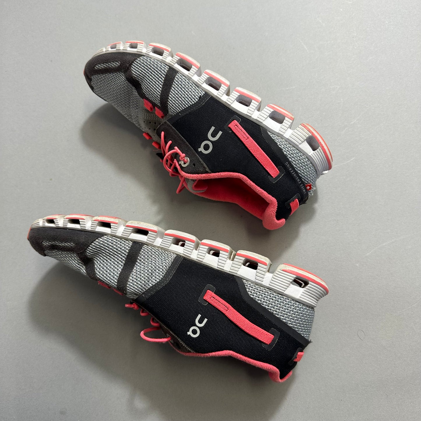 Black and pink running shoes on a gray surface.