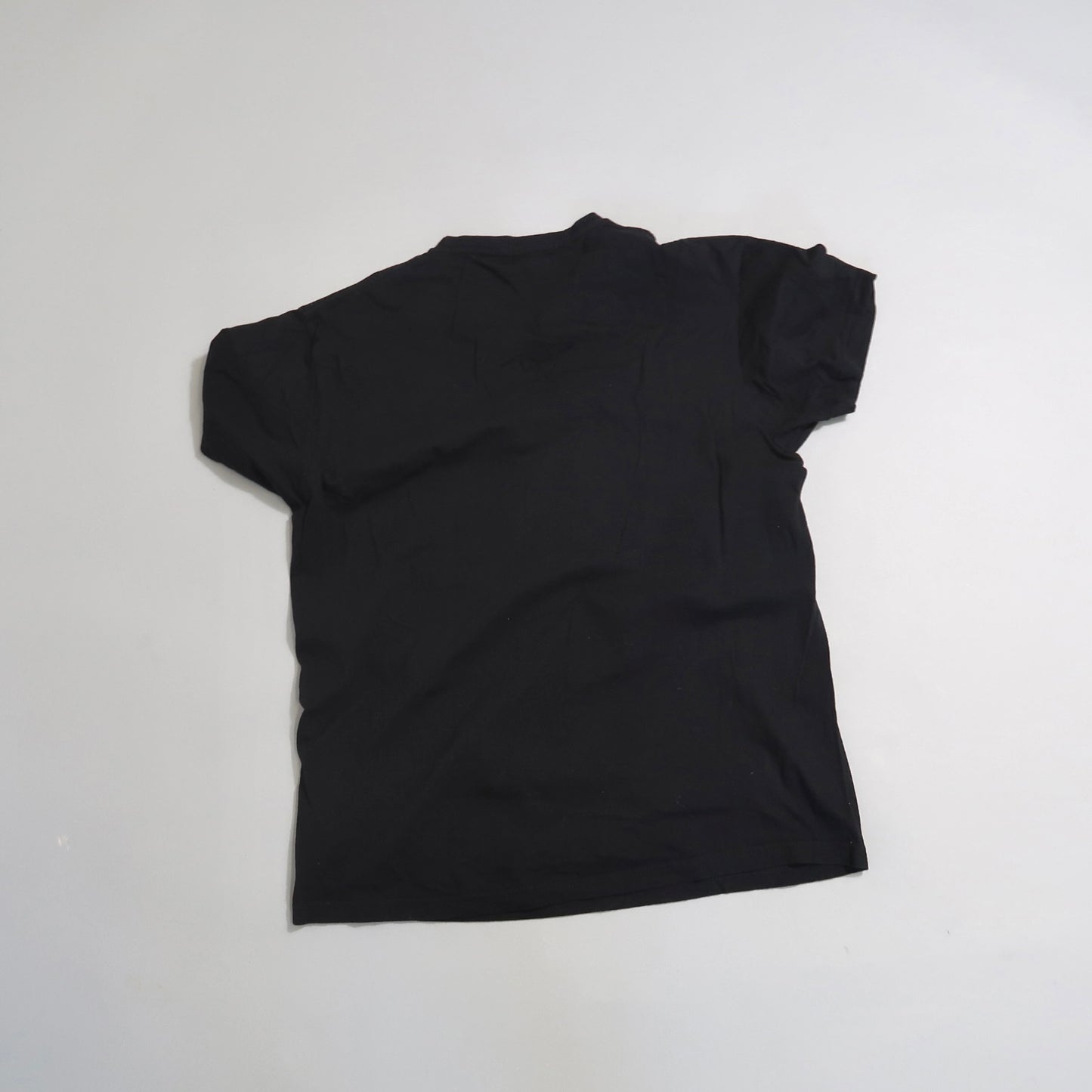 Black T-shirt lying flat on a light gray surface.
