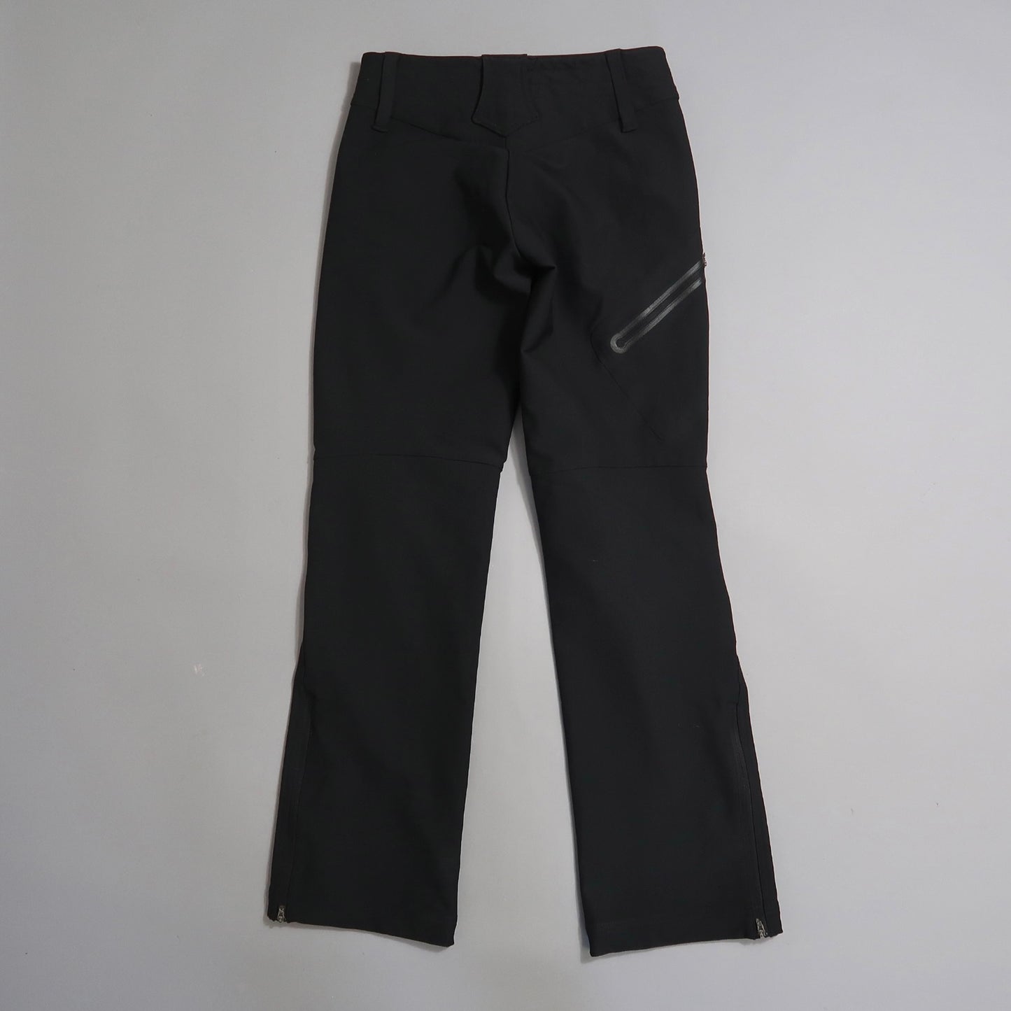 Black pants lying flat on a gray surface, rear view.