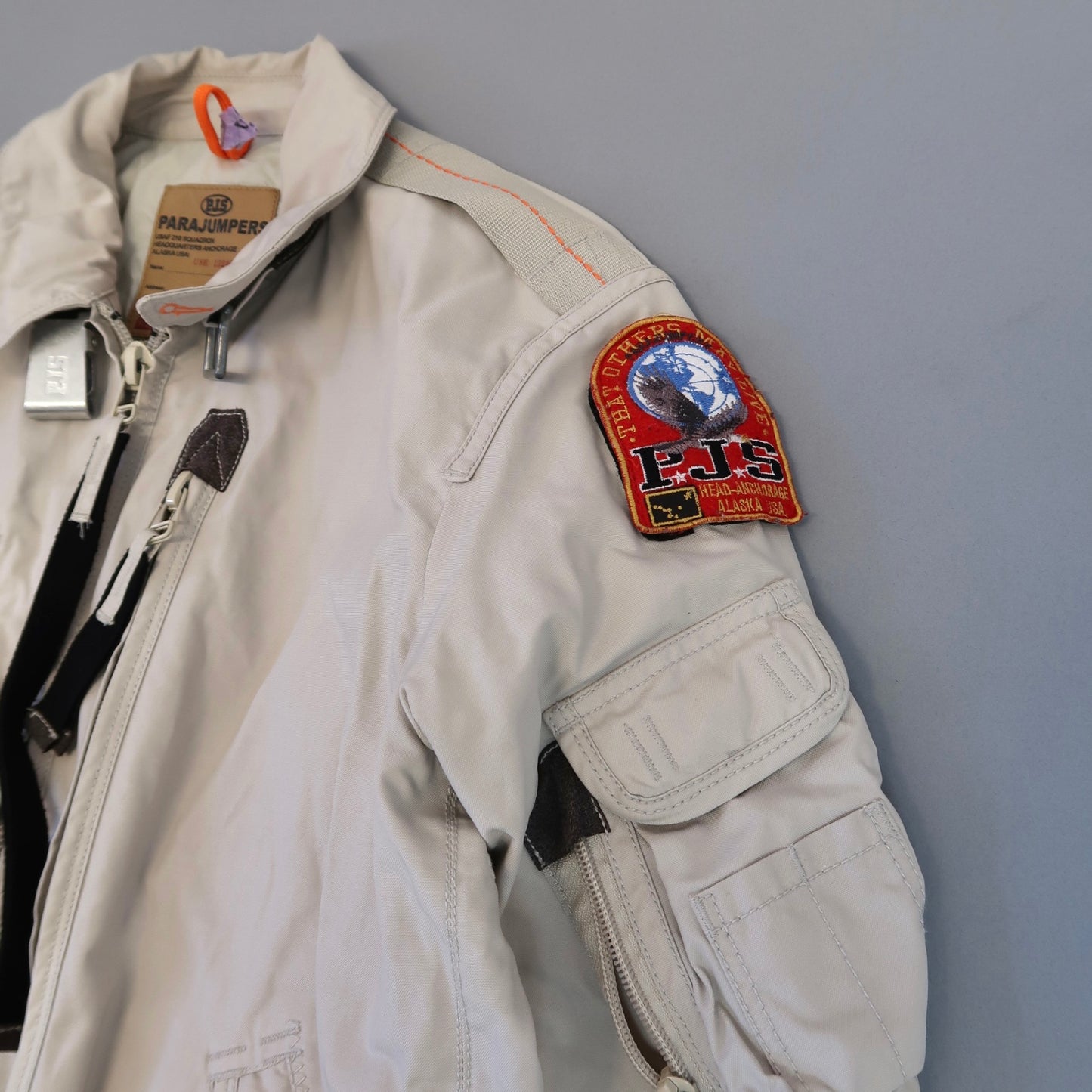 White jacket with a nullPJSnull patch on the shoulder against a gray background.