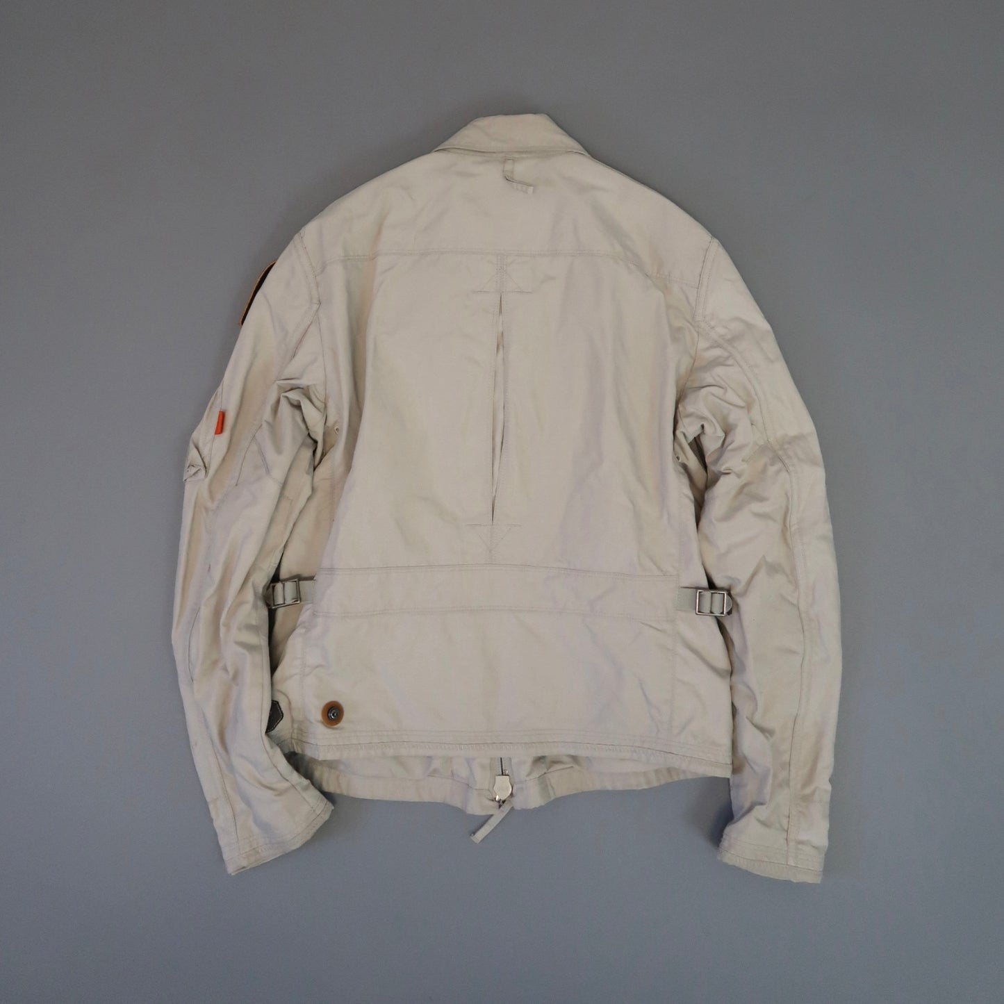 Beige jacket viewed from the back against a gray background.
