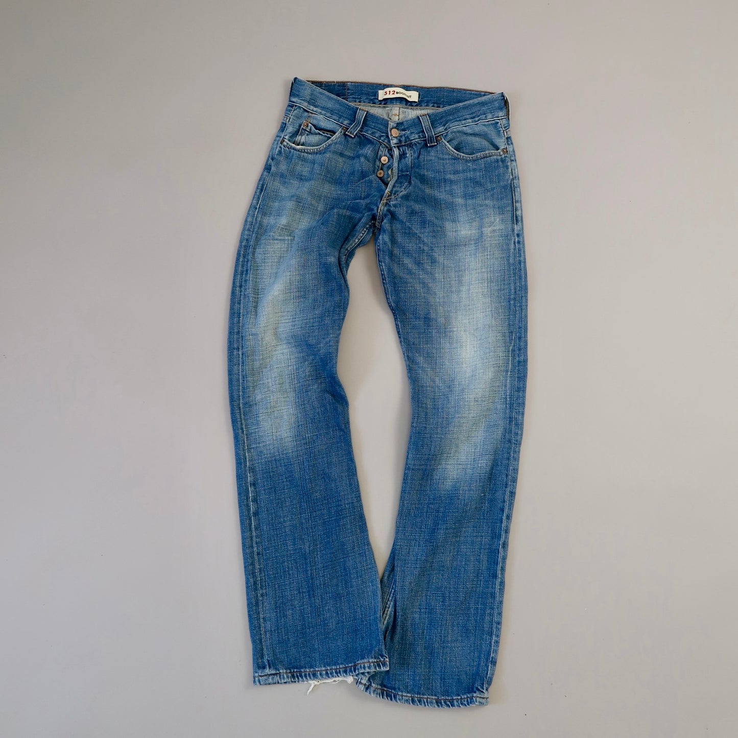 Blue jeans with a button fly on a gray background.