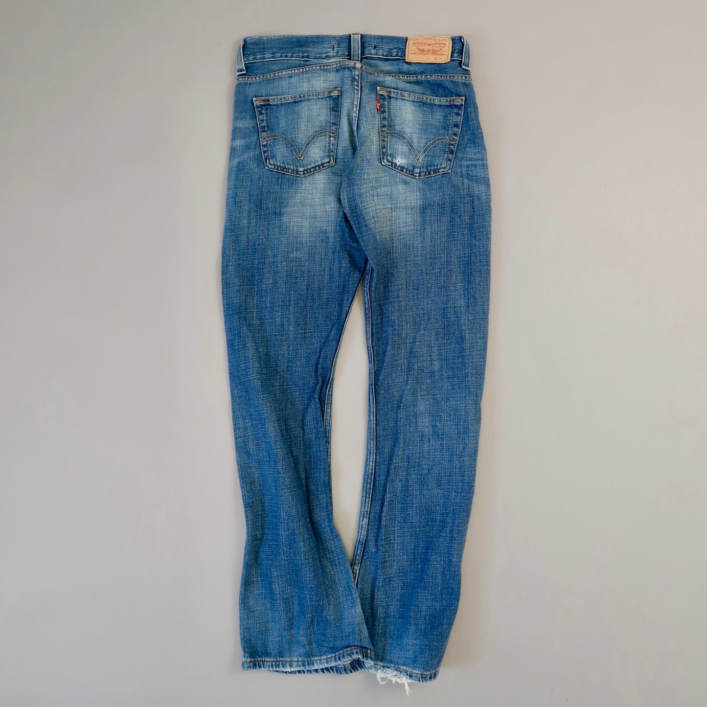 Back view of blue denim jeans on a plain background.