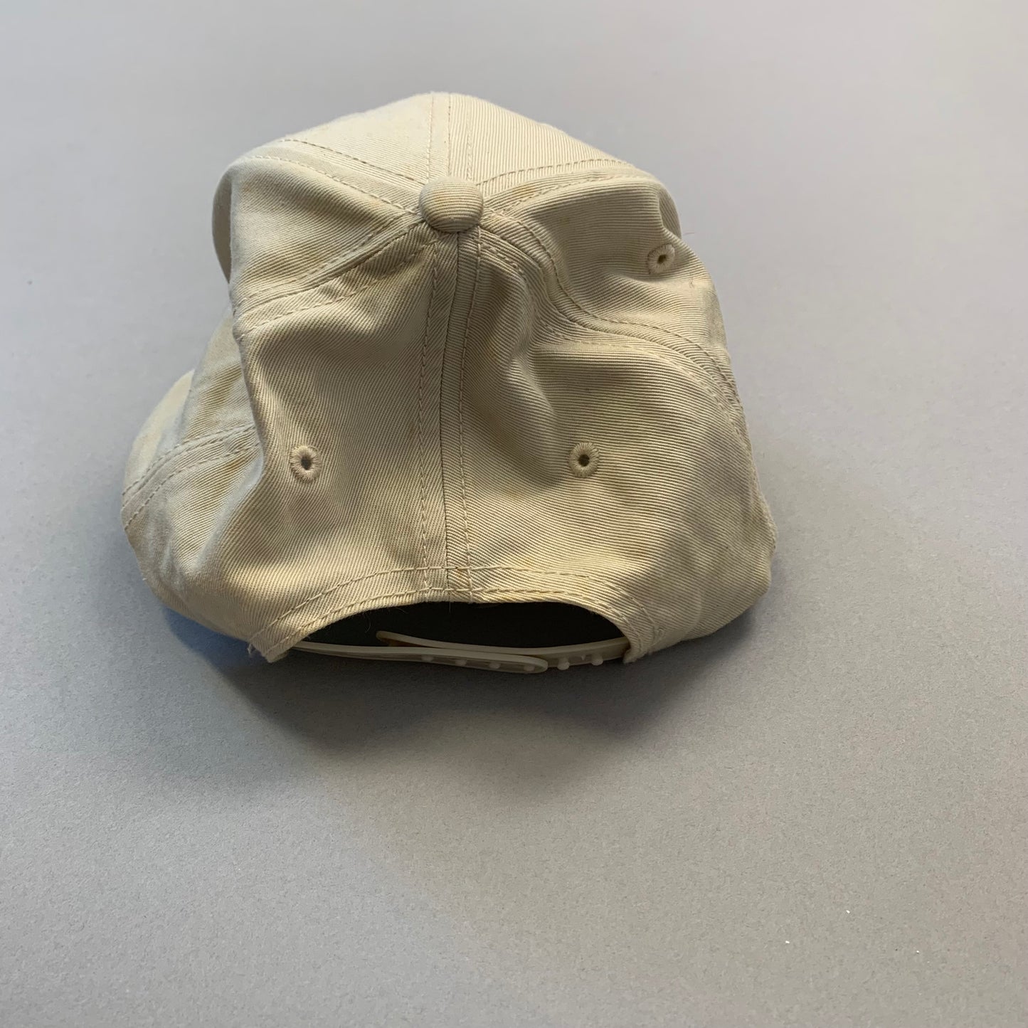 Beige baseball cap upside down on a gray surface.