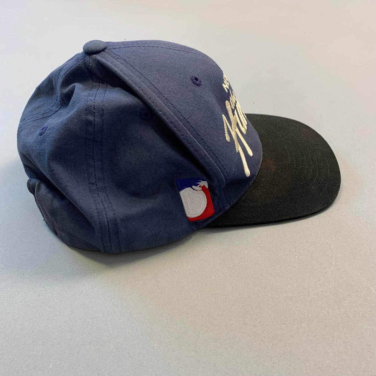 Blue and black baseball cap with embroidered logo on the side.