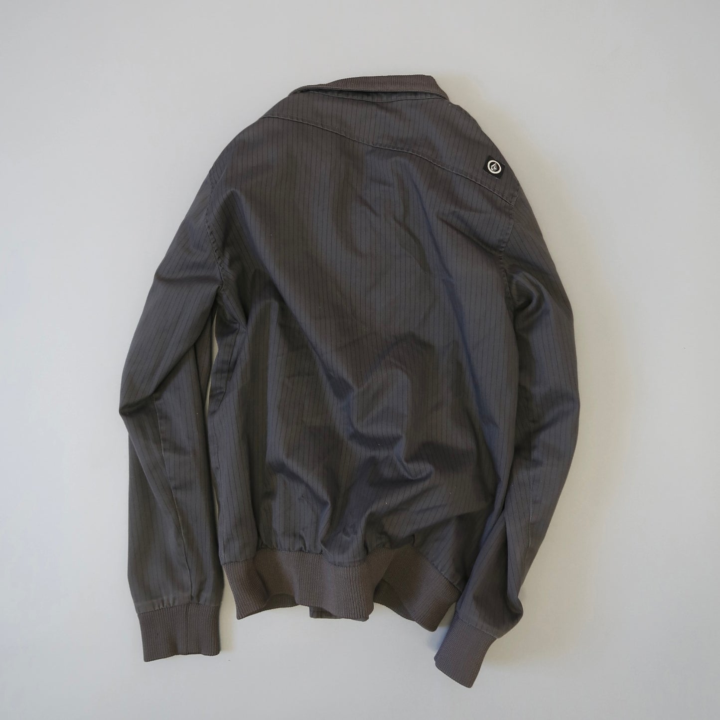 Dark striped jacket laid flat on a light background.