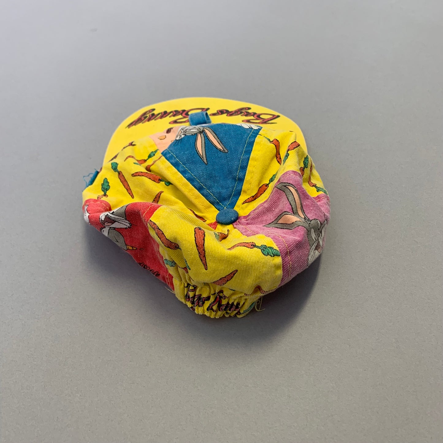 Yellow Bugs Bunny cap with carrot design on a gray background.