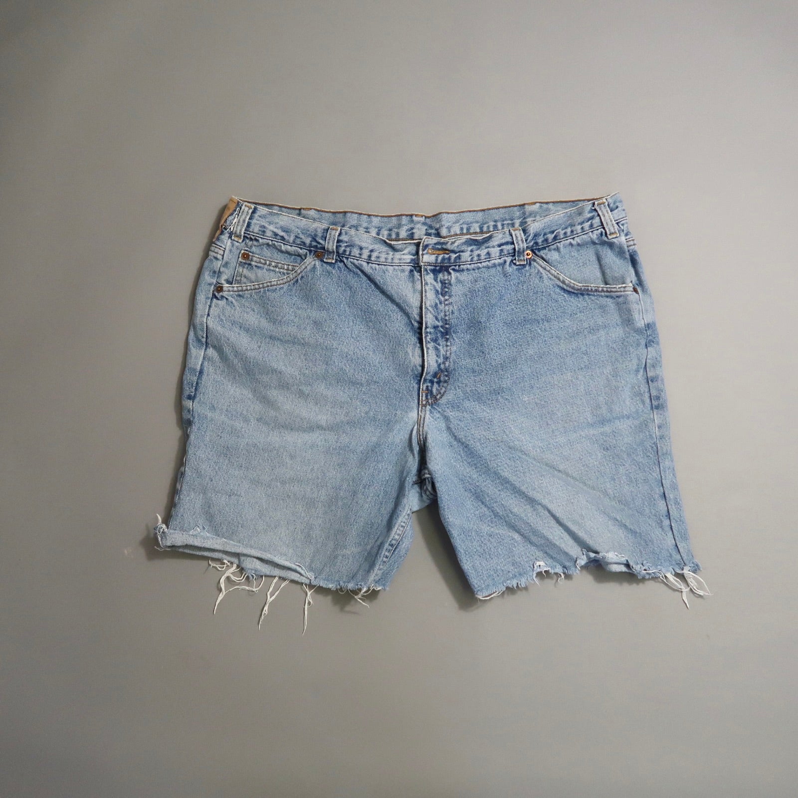 Light blue denim shorts with frayed hems on a neutral background.