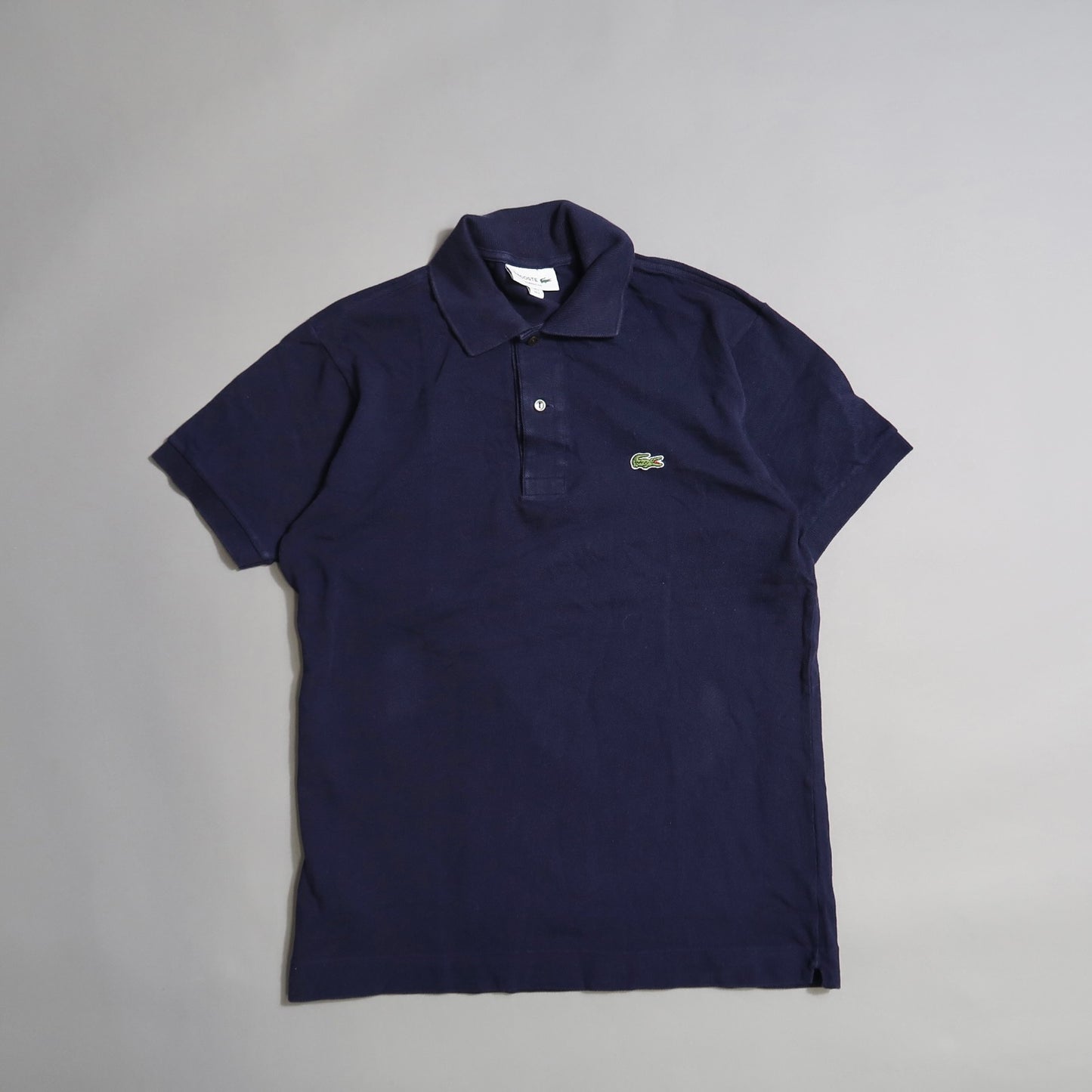 Navy blue polo shirt with a crocodile logo on a plain background.