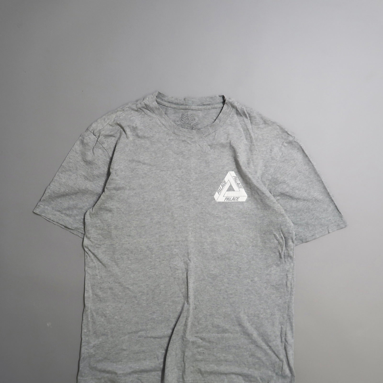 Gray T-shirt with triangular logo on the left chest.