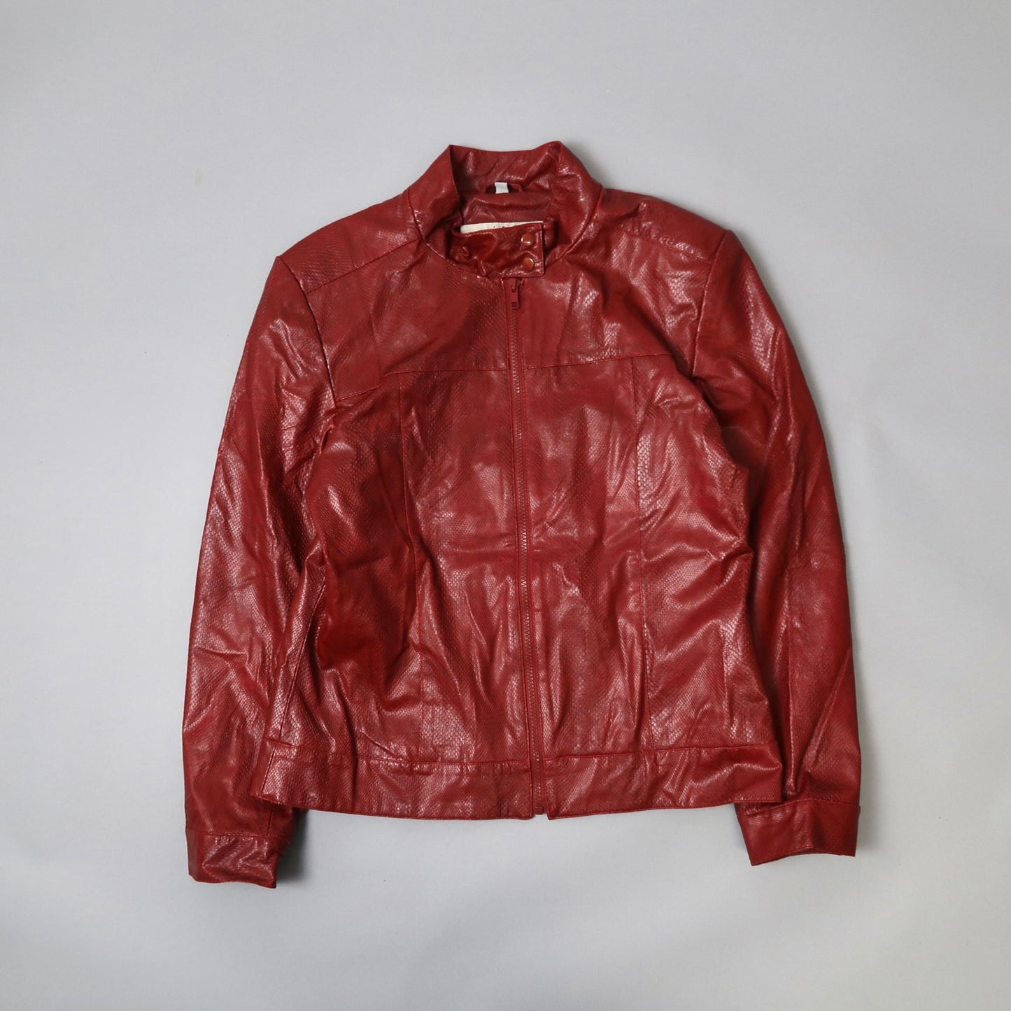 Red leather jacket with zipper and collar on a light background.