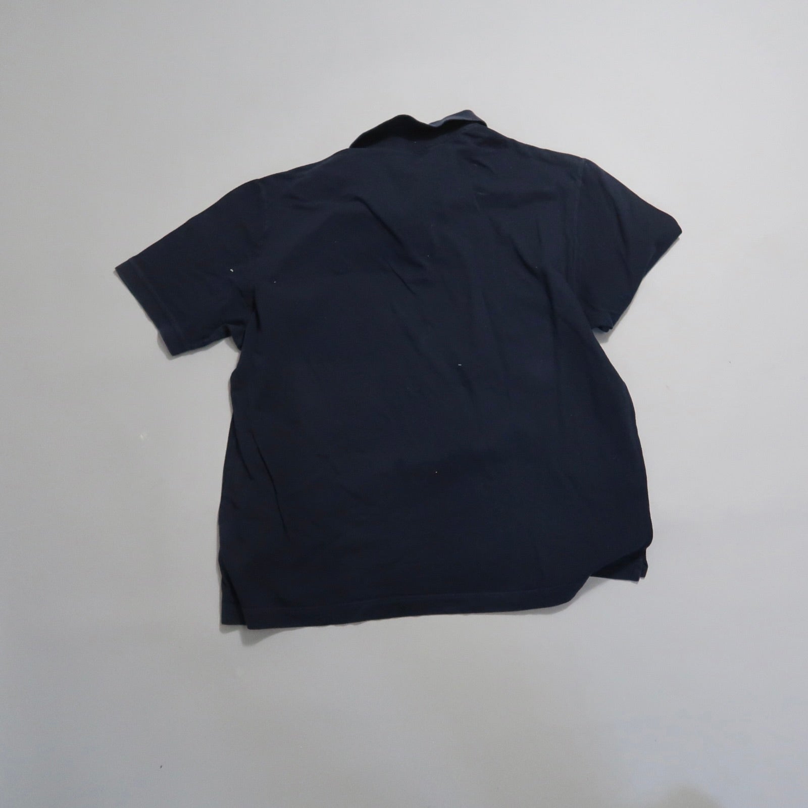 Back view of a plain black t-shirt on a flat surface.
